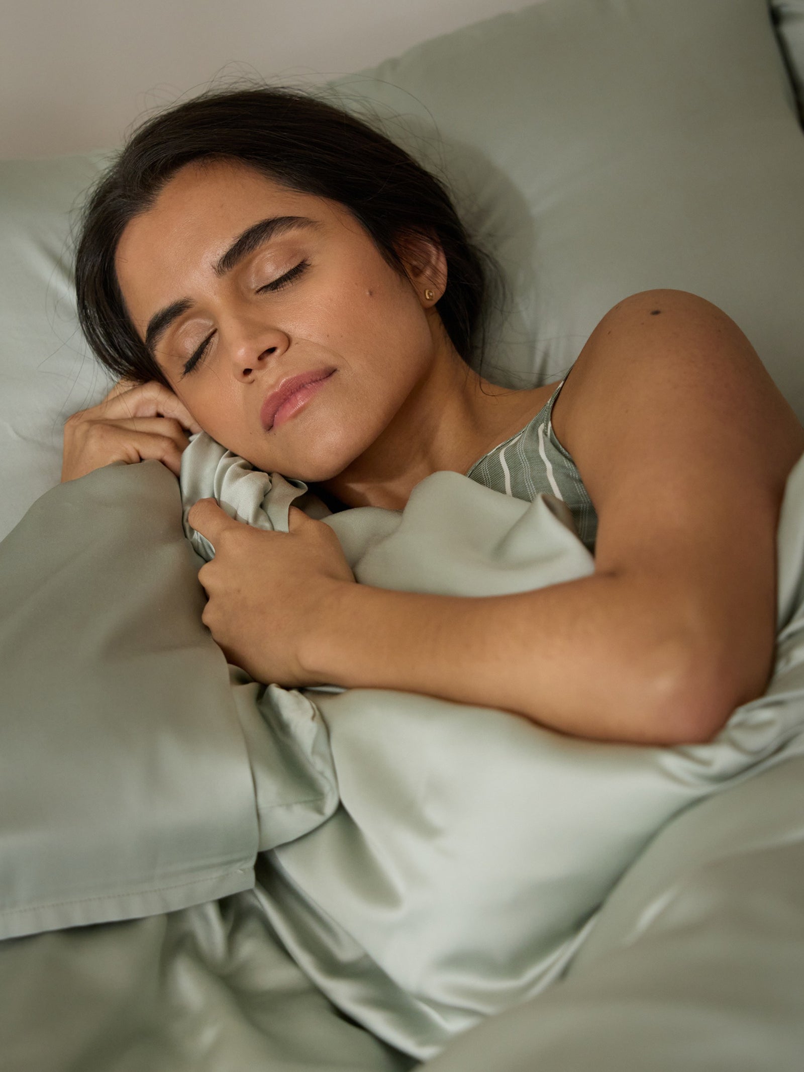 A woman sleeps peacefully in a bed with laurel bedding standard/king. 