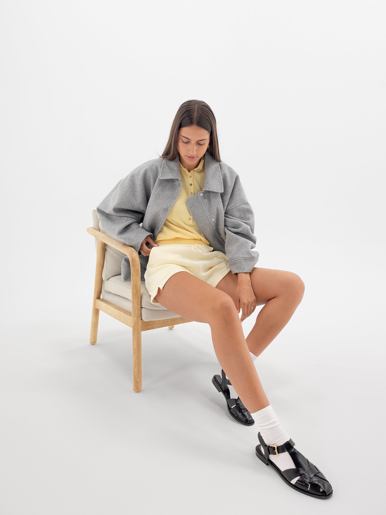 Lemonade CityScape Shorts. The shorts are being worn by a female model sitting on a chair. The model is wearing dress shoes. The background it a white background. 