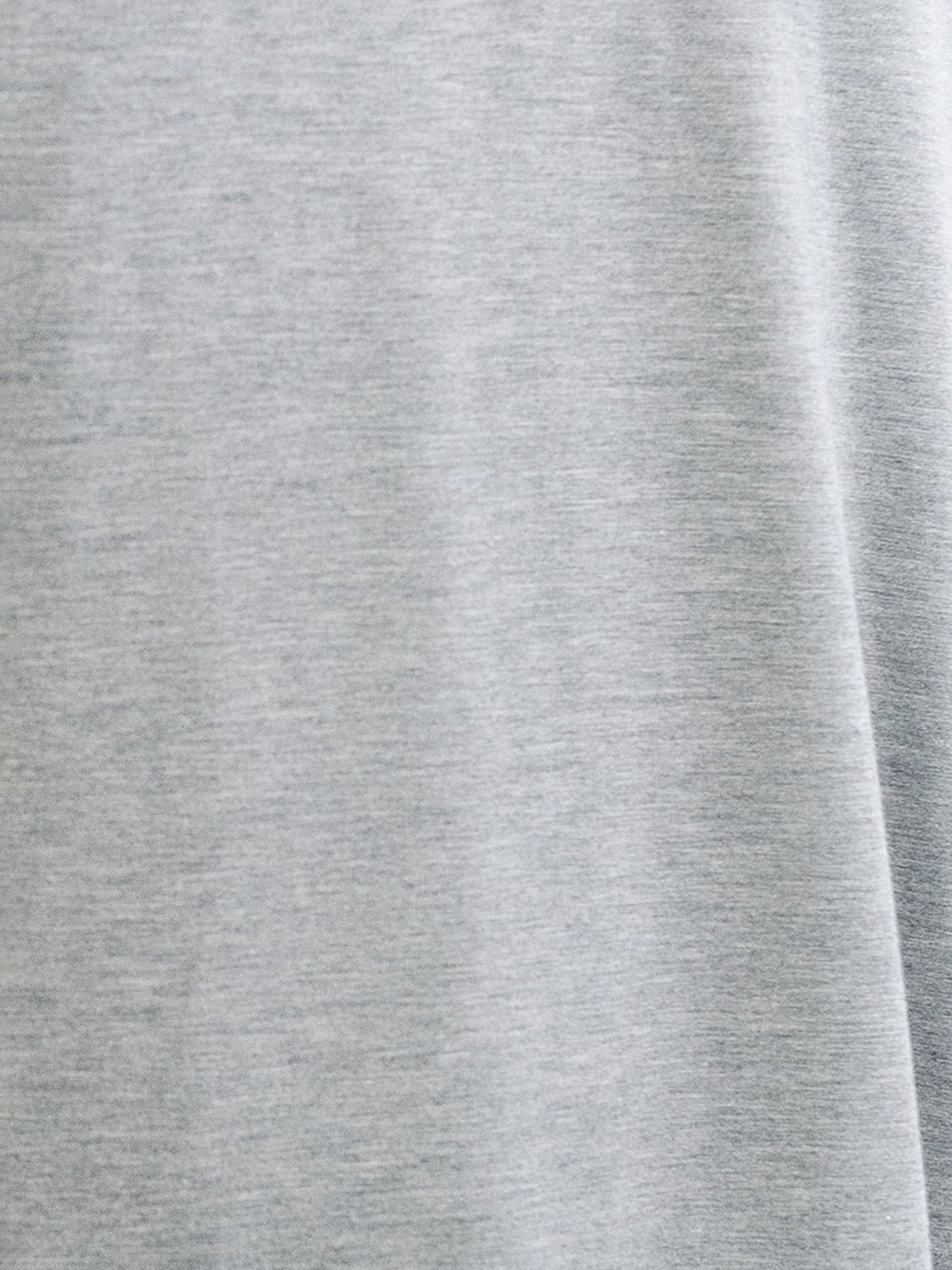 A close-up view of the smooth, light gray fabric from the Men's Stretch-Knit Long Sleeve Bamboo Pajama Jogger Set by Cozy Earth. The material appears exceptionally soft and comfortable, likely due to its bamboo fabric blend. The image captures the subtle weave and slight variations in the shade of this premium sleepwear fabric. 