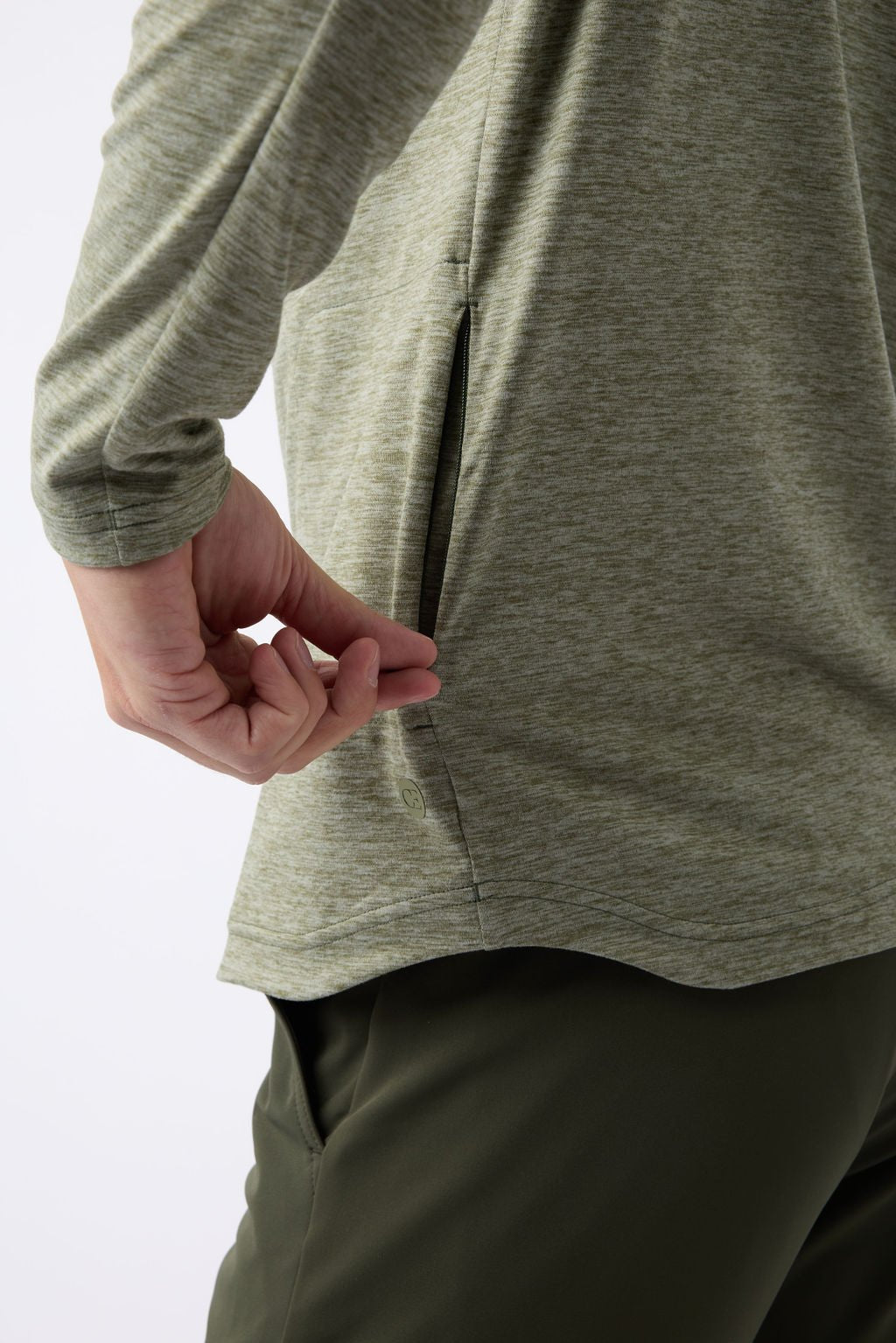 A person is wearing a Cozy Earth's Men's Lightweight Performance Hoodie, featuring long sleeves in a green hue with visible side pocket details. They are also dressed in dark green pants against a plain white background. 
