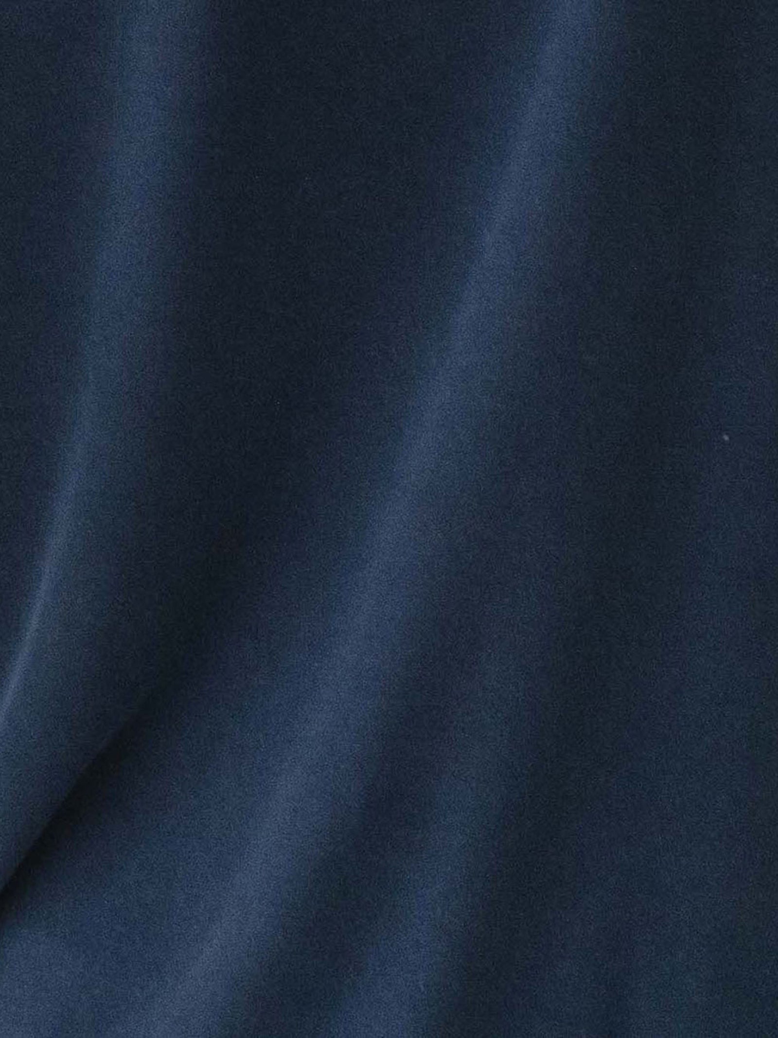 Close-up of the Men's Stretch-Knit Long Sleeve Bamboo Pajama Jogger Set by Cozy Earth in a dark blue hue, showcasing its silky and smooth fabric. The material exhibits slight folds and waves that create variations in light and shadow across its surface, imparting an impression of softness and luxury. 