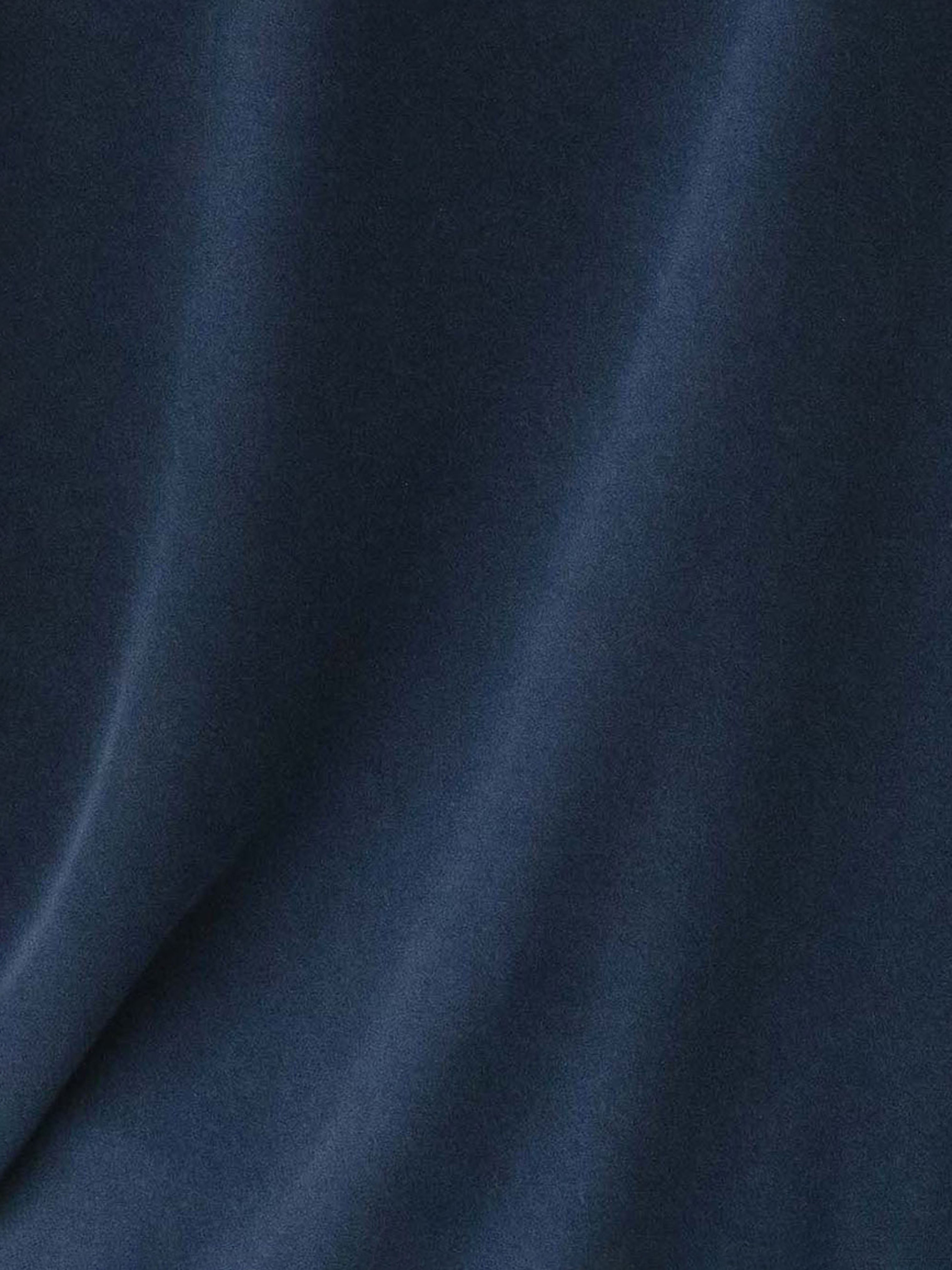 The Men's Stretch-Knit Short Sleeve Bamboo Pajama Set by Cozy Earth features a smooth, dark blue fabric with soft, flowing folds that create a wave-like texture. The slightly shiny surface of the material subtly reflects light, accentuating its elegant appearance. 