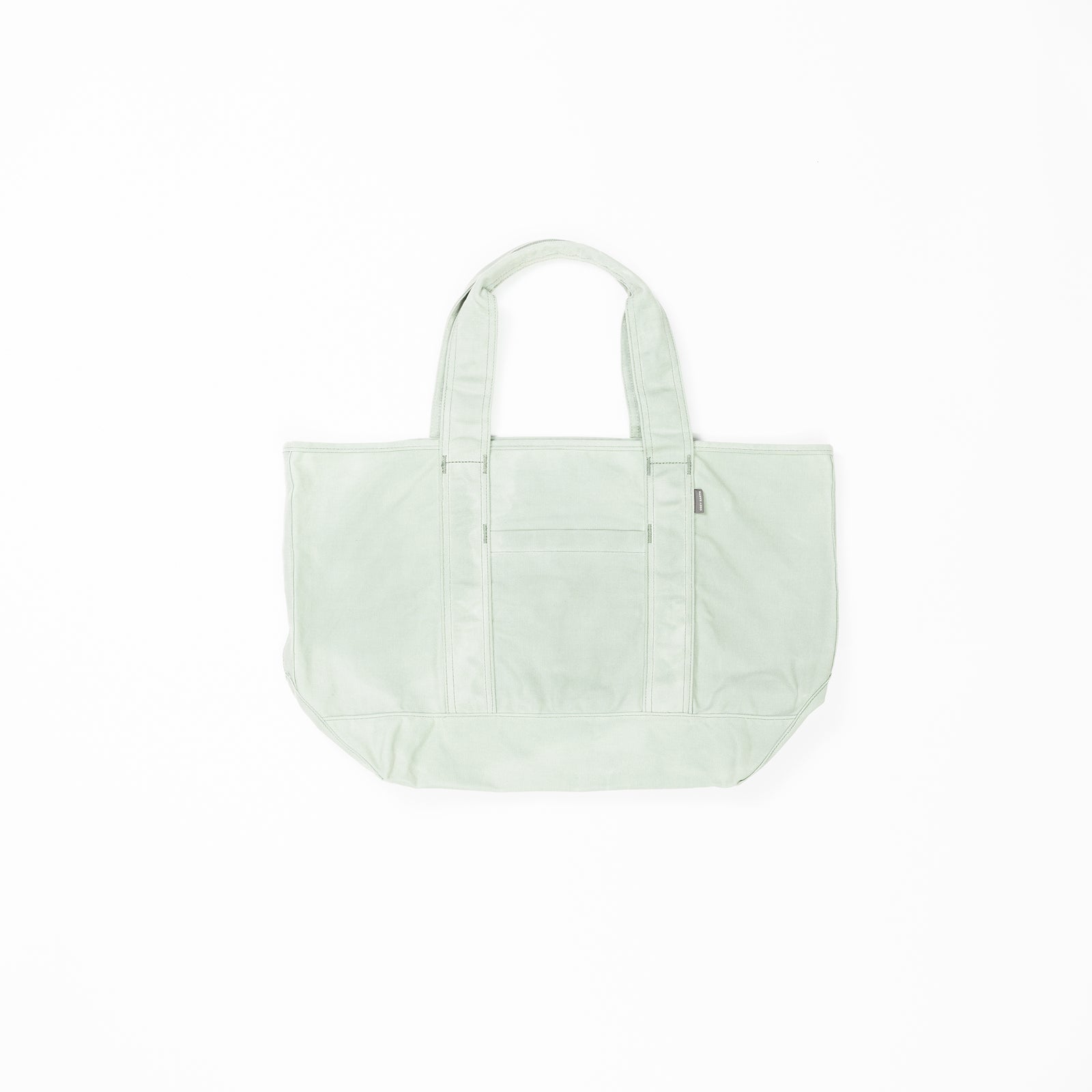 A light green Waxed Canvas Tote from Cozy Earth with two handles is centered on a white background. The tote bag features a front pocket with a zipper, visible seams, and a rectangular shape, providing ample storage space. 