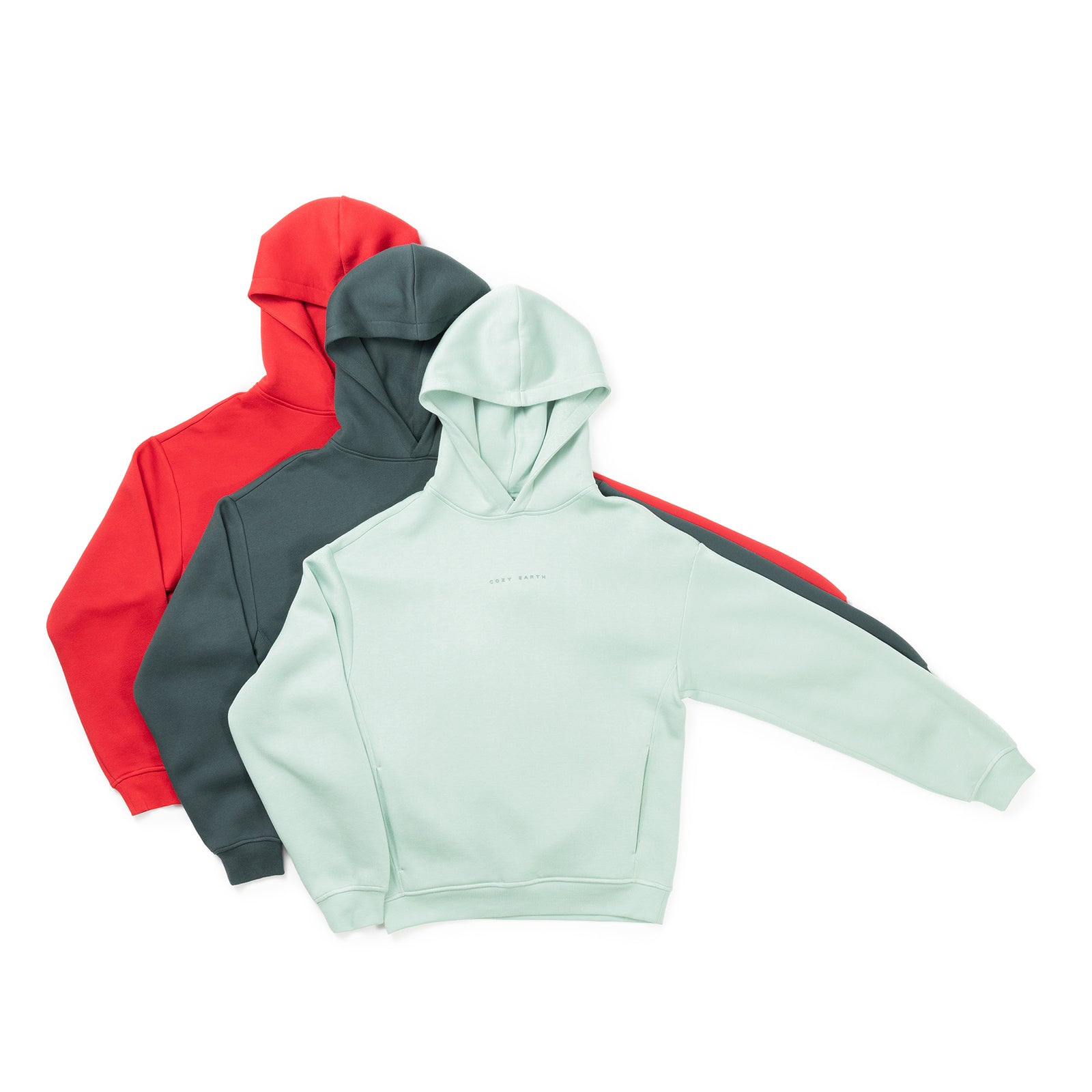 Three Women’s CityScape Hoodies from Cozy Earth are displayed on a white background, layered on top of each other. The hoodies come in light green, dark green, and red colors. Each one features a simple, clean design with a hood and long sleeves. 