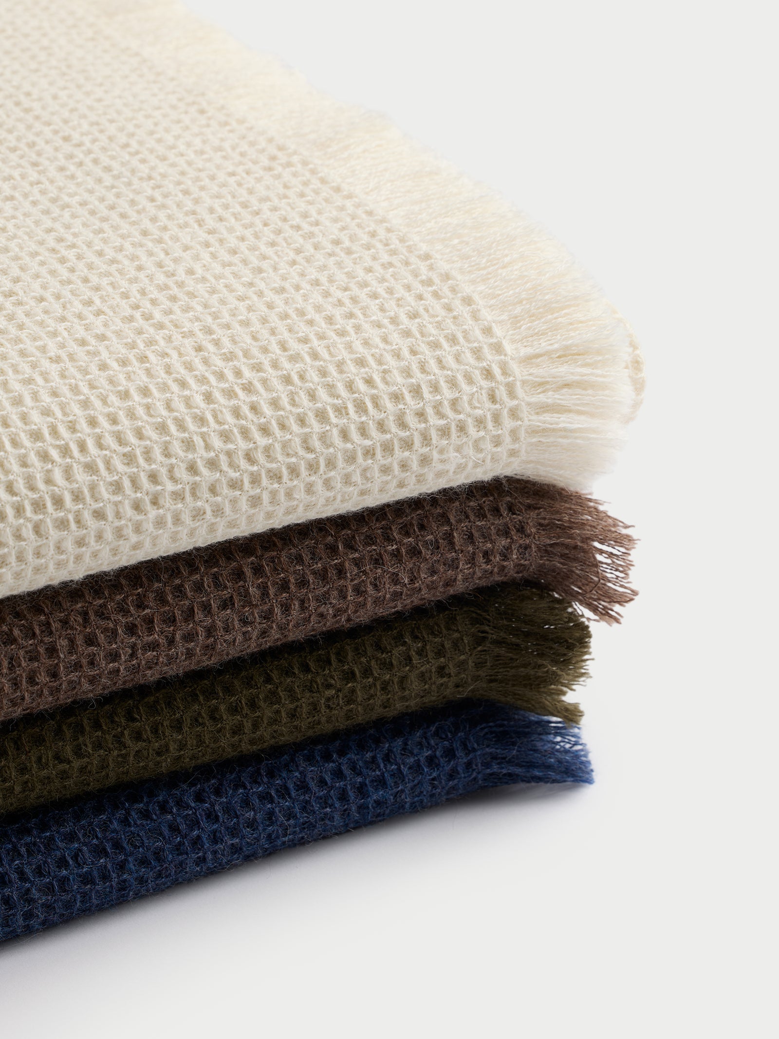 Four colors of alpaca throws stacked on top of each other 