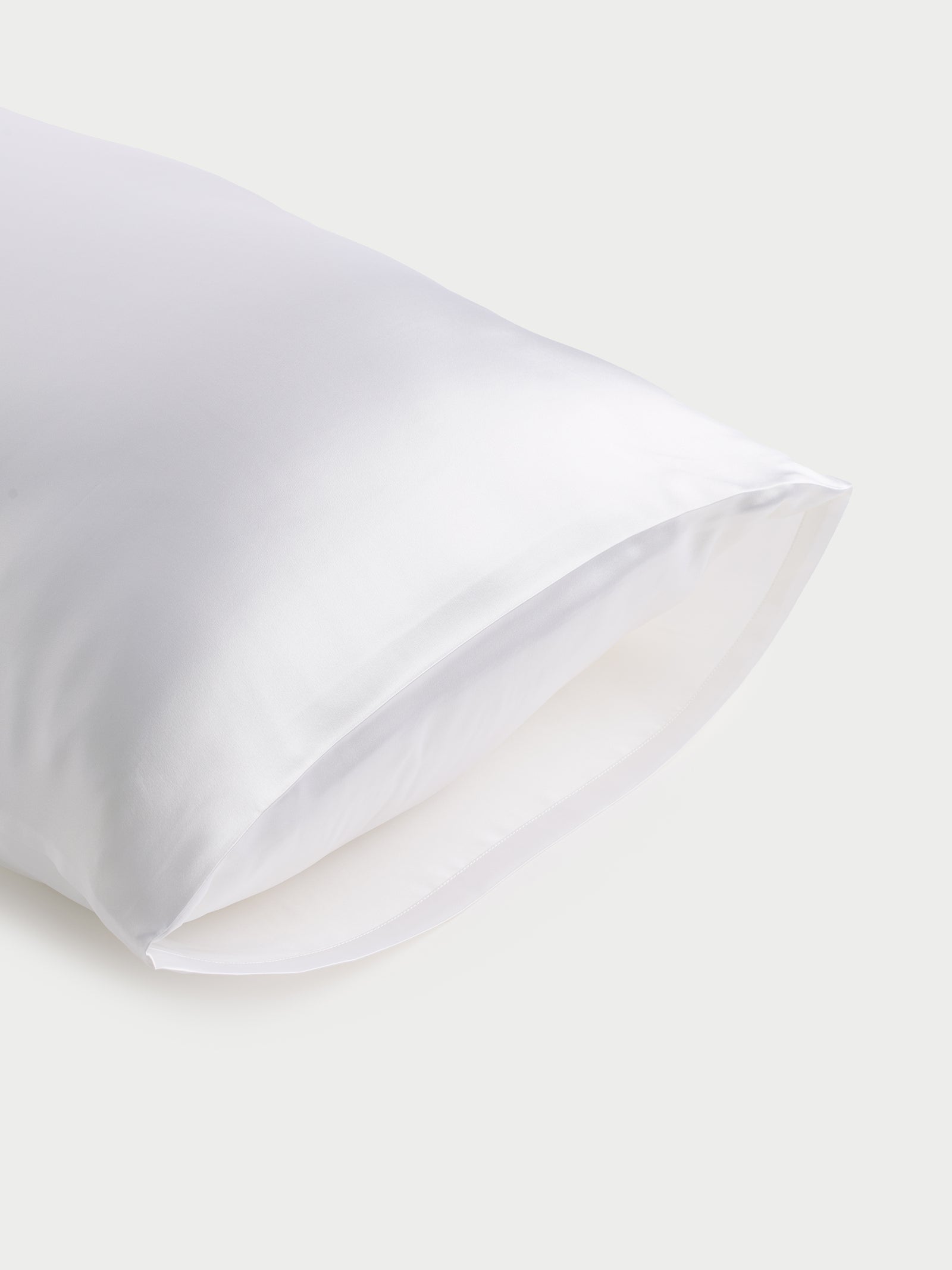 The Cozy Earth Silk Pillowcase, with its smooth and glossy texture, is showcased against a light gray background. The fabric drapes softly, accentuating its luxurious and sleek appearance. 