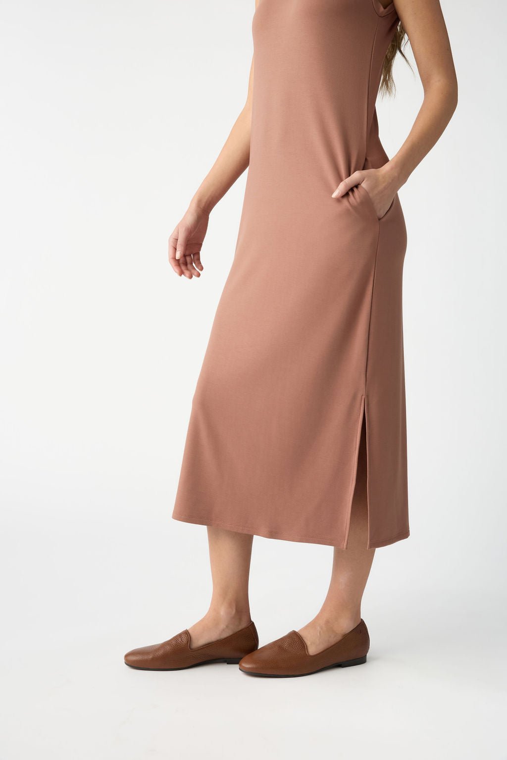 Dressed in the Women's Brushed Bamboo Sleeveless Midi Dress by Cozy Earth, a woman with brown loafers stands against a plain white backdrop. Her rust-colored dress features stylish side slits, though her head is not visible in the image. 