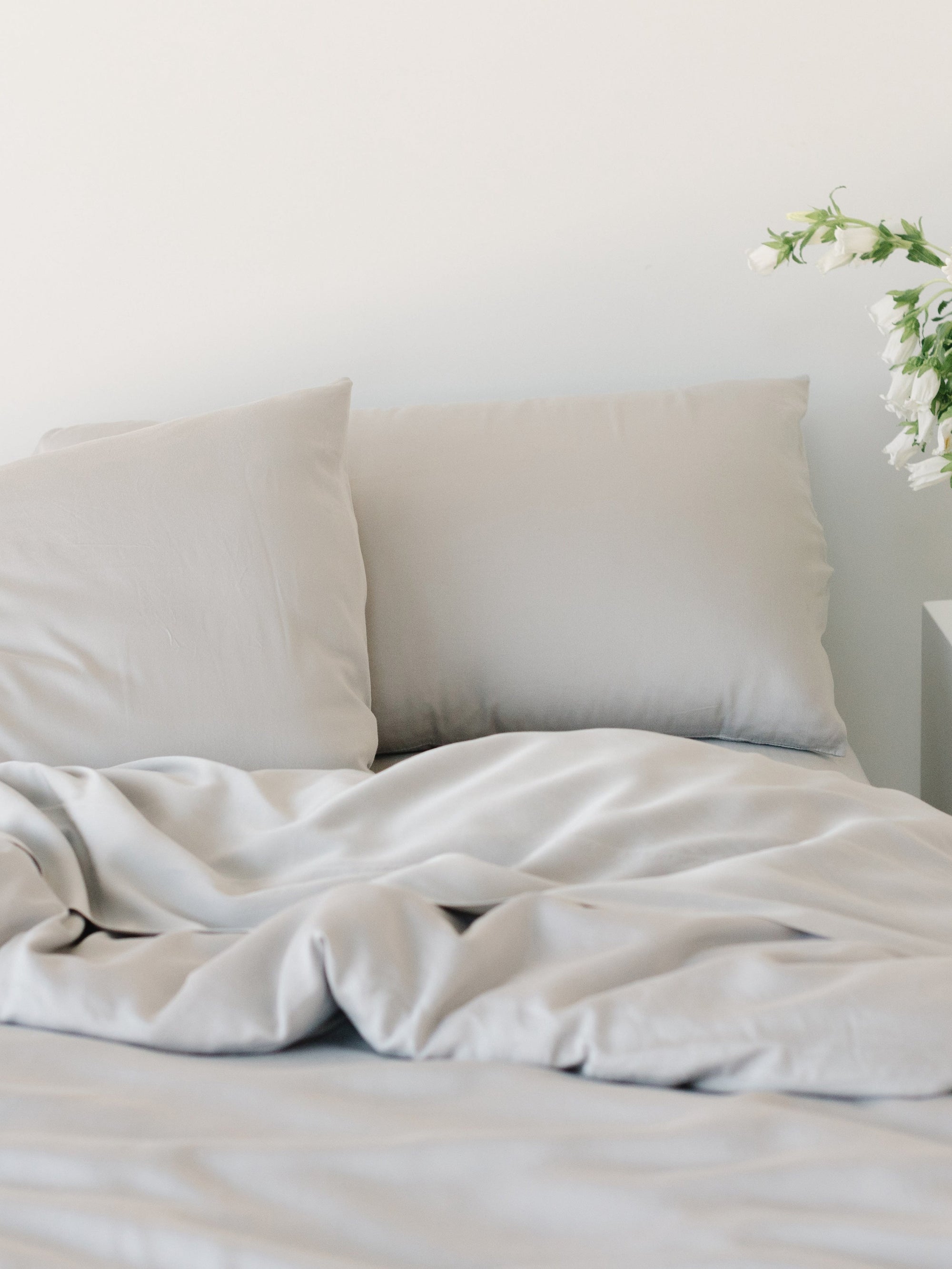 Unmade bed with light grey bedding 