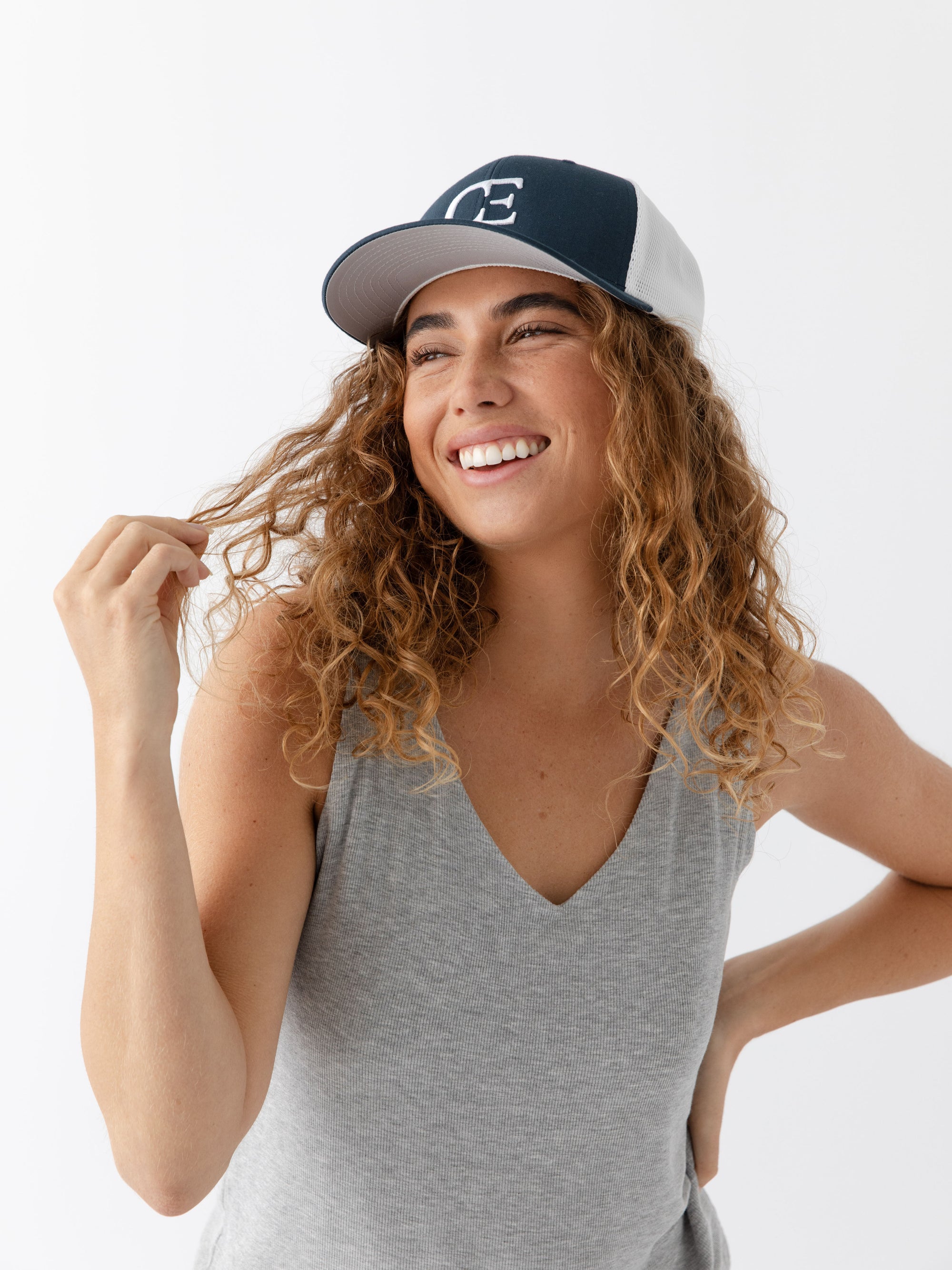 Woman wearing a Navy and white cap with a CE logo on a light gray background 