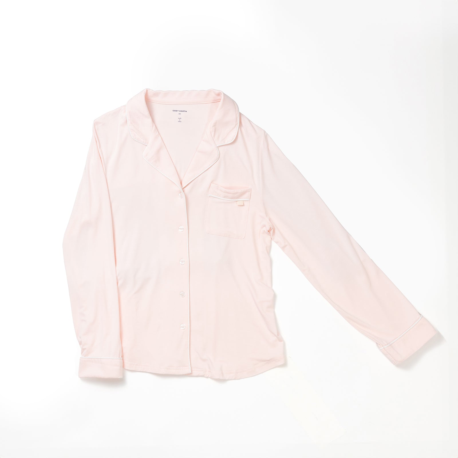 A Women's Long Sleeve Bamboo Pajama Top in Stretch-Knit TALL from HIDE, featuring a light pink color, long sleeves, a button-down front with a collar, and a small chest pocket. The fabric appears soft and comfortable as the shirt is displayed flat against a white background. 