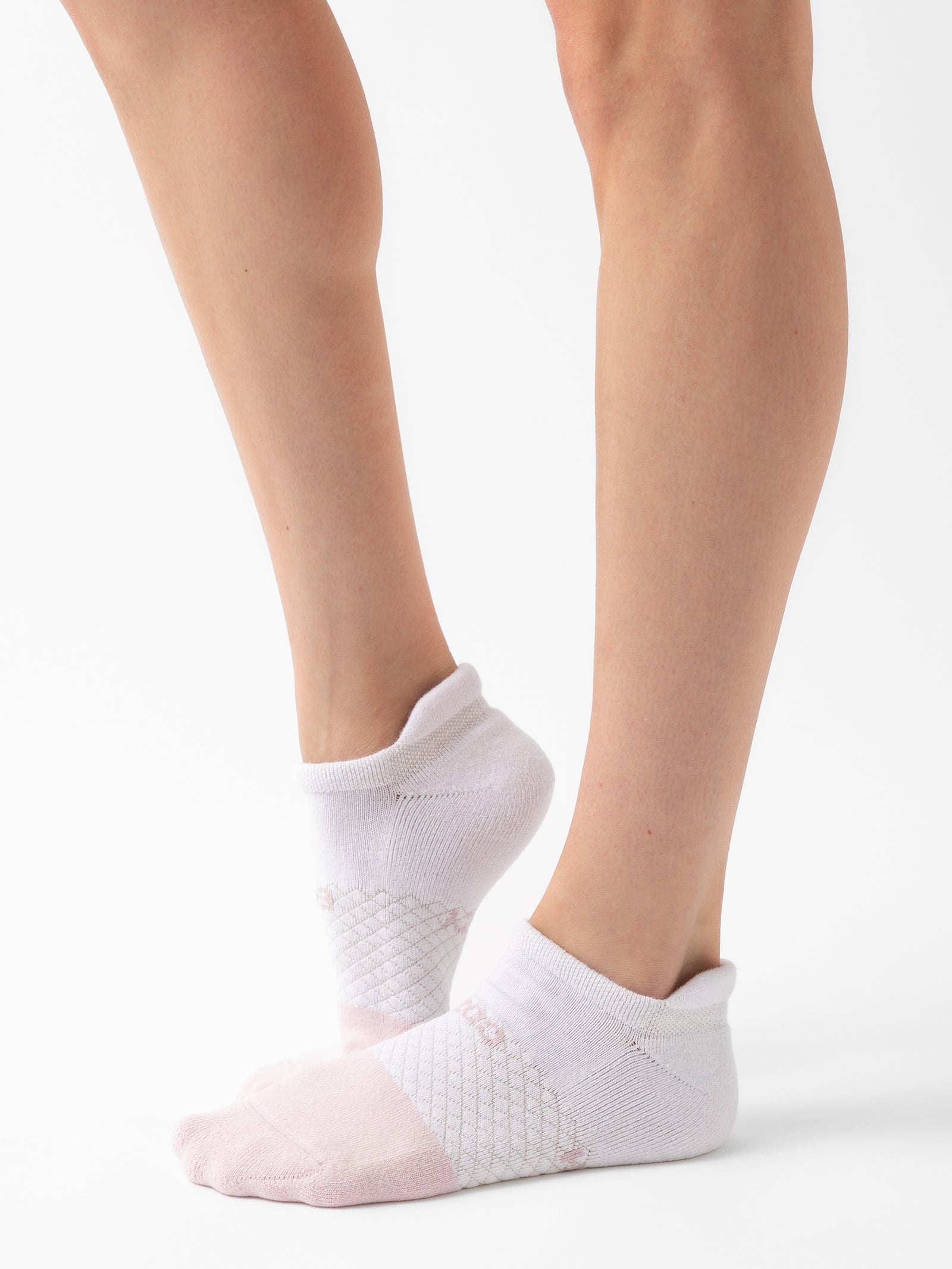 A pair of feet wearing Cozy Earth's Essential Ankle Socks, showcasing a light pink toe area against the white sock. The pristine white background emphasizes the simple yet stylish design and snug fit of these socks from the Essential Ankle Sock 2-Pack on the person's feet. 