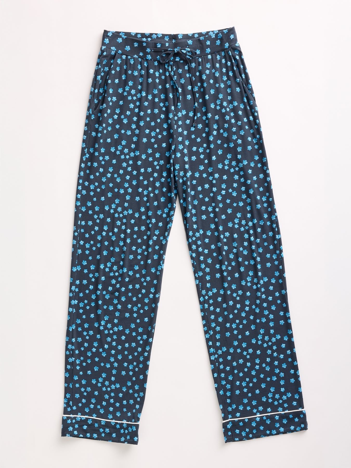 Dark blue pajama pants with a light blue floral pattern from Cozy Earth's Women's Bamboo Stretch-Knit Long Sleeve Pajama Set feature an elastic waistband, drawstring, and white piping near the cuffs. They are displayed on a light background. 