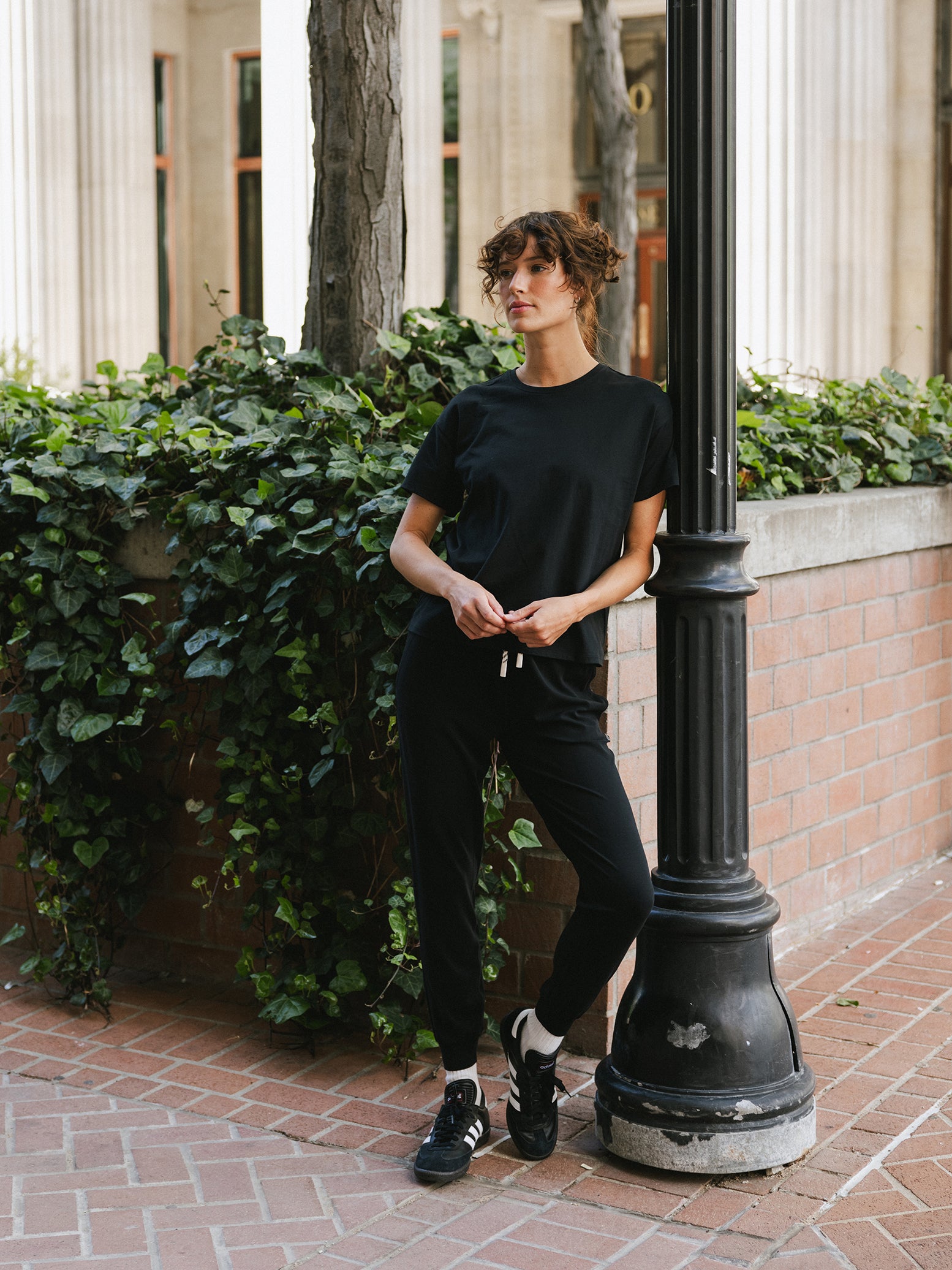 Woman on street corner wearing black tee and joggers 