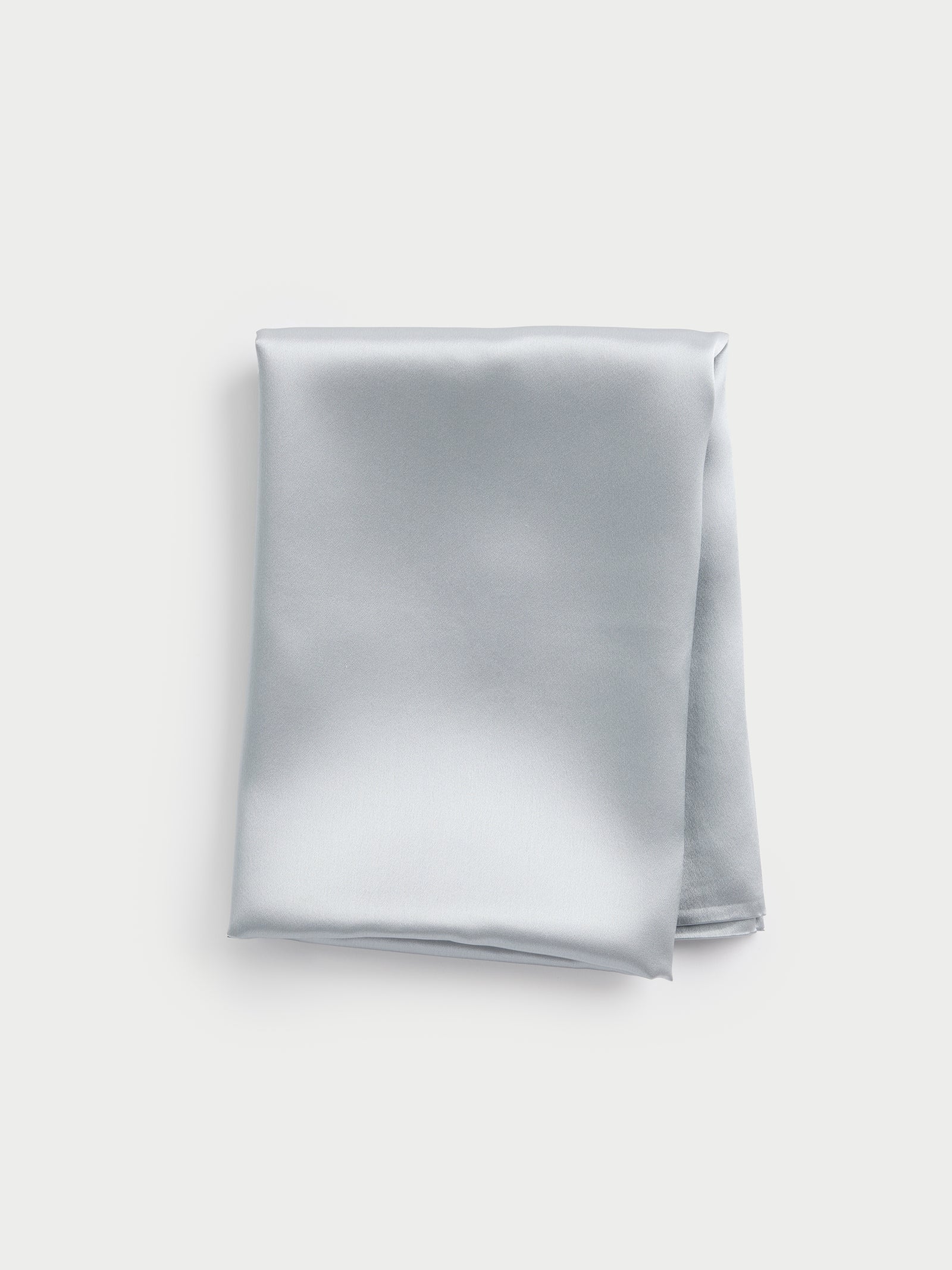 A neatly folded silk pillowcase in a light gray hue from Cozy Earth, displayed on a plain white background, highlighting its smooth and glossy texture. 