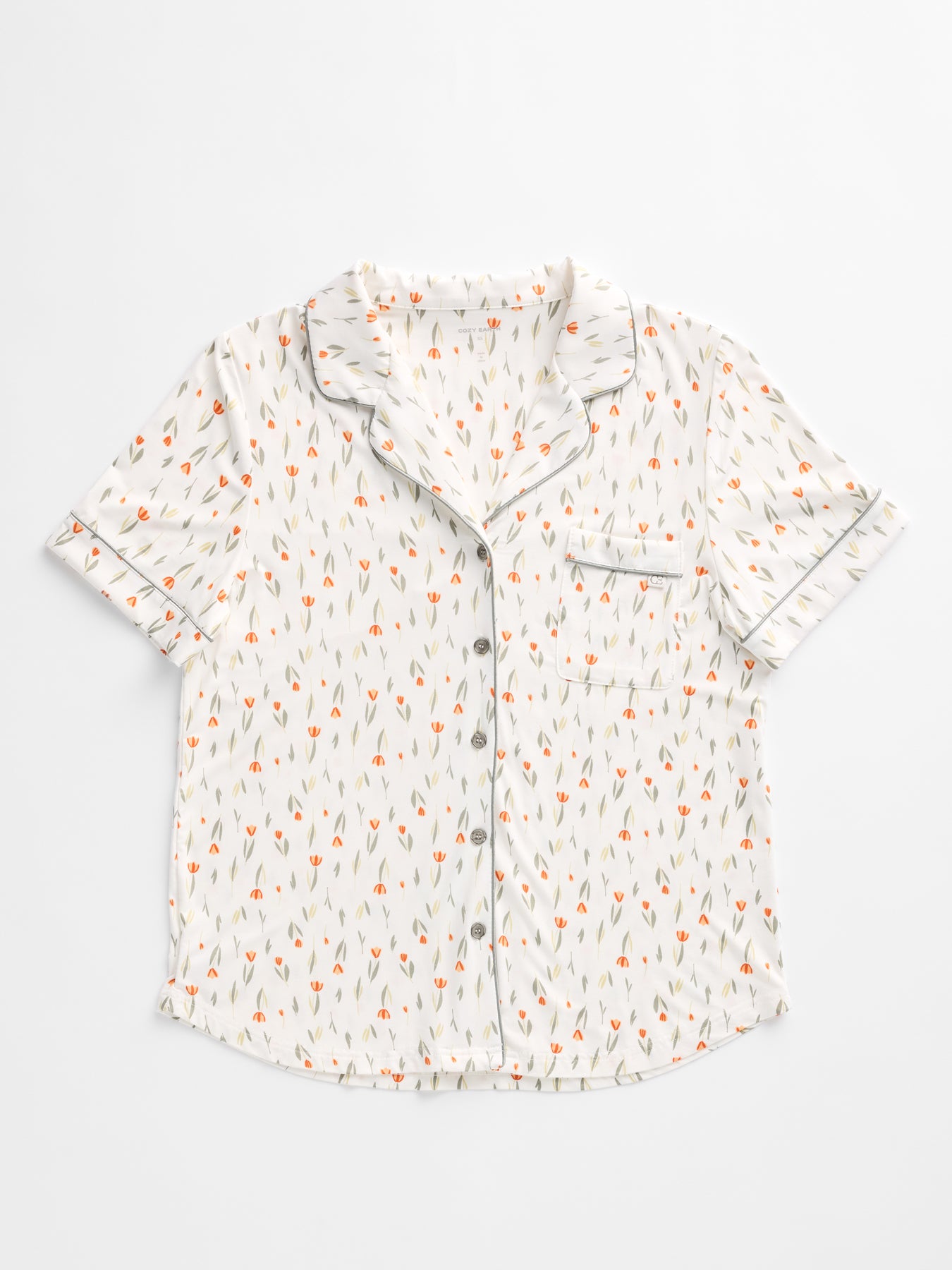 The Women's Bamboo Stretch-Knit Short Sleeve Pajama Top by HIDE features a white base with small orange and green florals, a collar, front pocket, button closures, and dark piping along the edges.