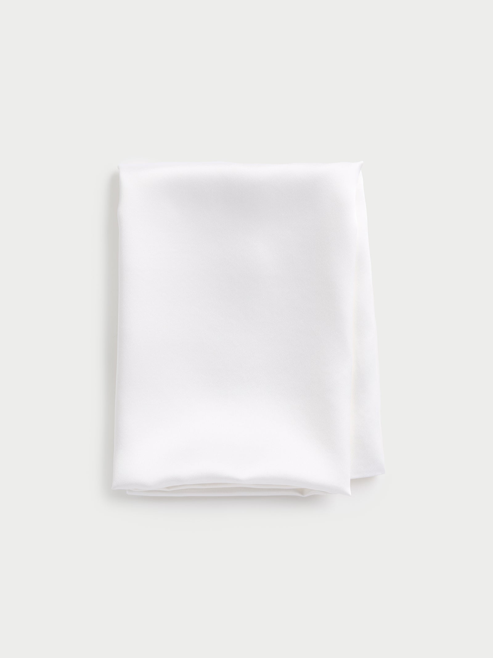 A folded Silk Pillowcase by Cozy Earth set against a light gray background. 