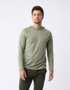 A man with short hair wears the Men's Lightweight Performance Hoodie by Cozy Earth in olive green, paired with dark pants. He has a neutral expression and stands against a plain white background. |Color:Heather Olive
