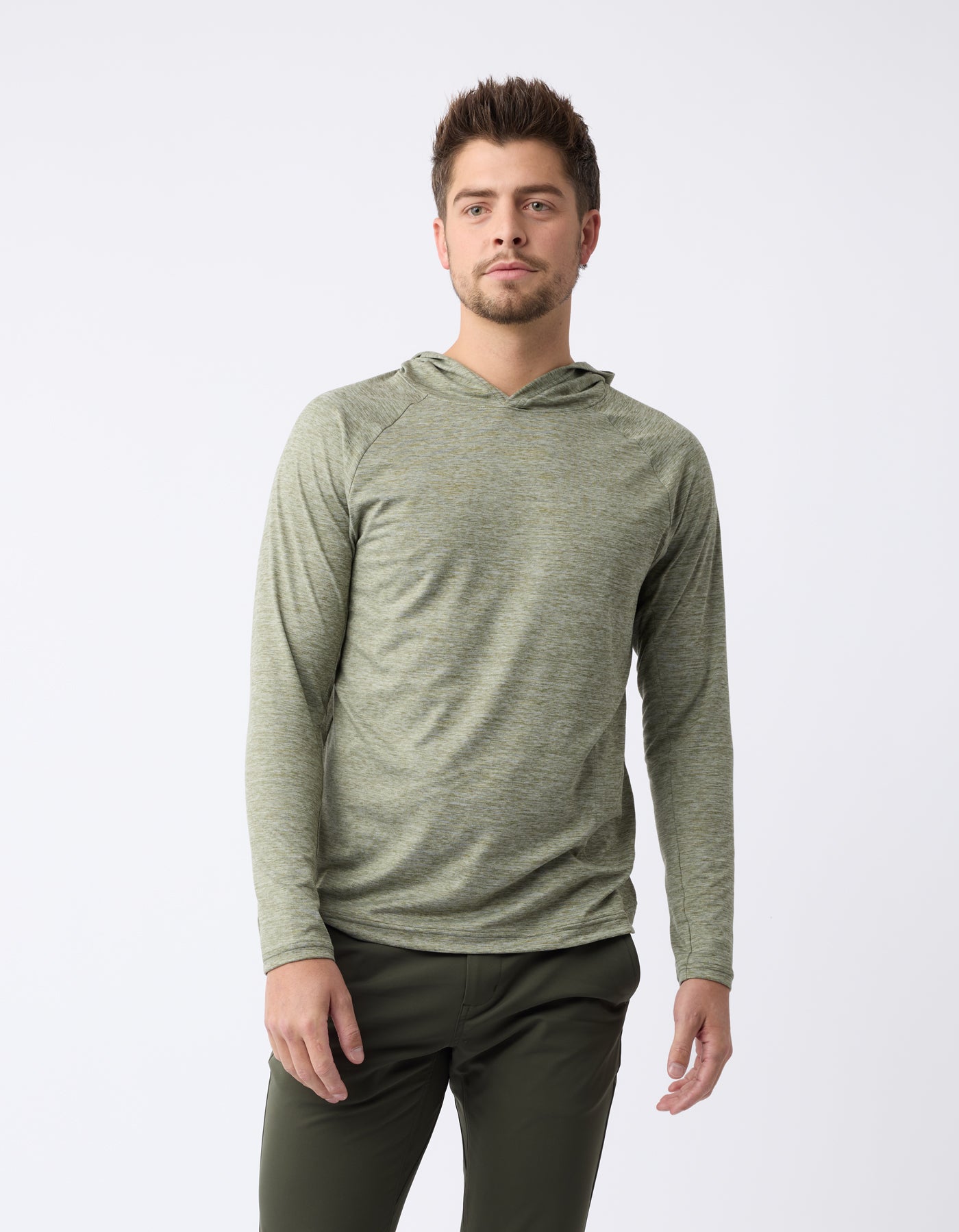 A man with short hair wears the Men's Lightweight Performance Hoodie by Cozy Earth in olive green, paired with dark pants. He has a neutral expression and stands against a plain white background. |Color:Heather Olive