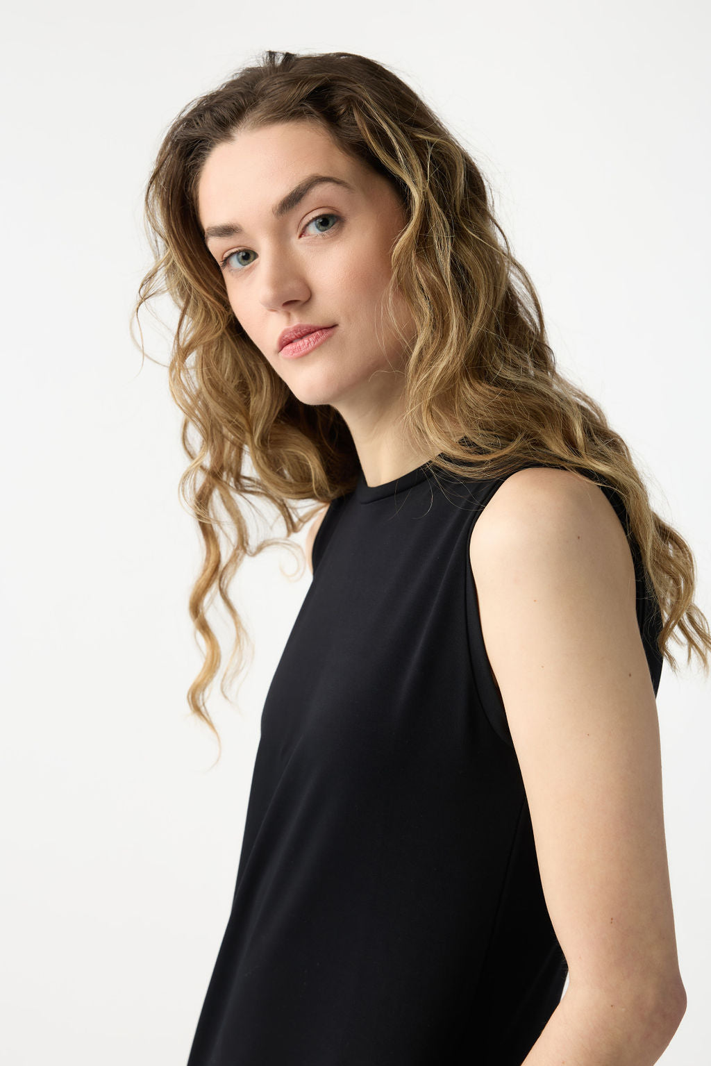 A woman with long wavy hair wears a Cozy Earth Women's Brushed Bamboo Sleeveless Midi Dress, gazing at the camera against a plain white background. 