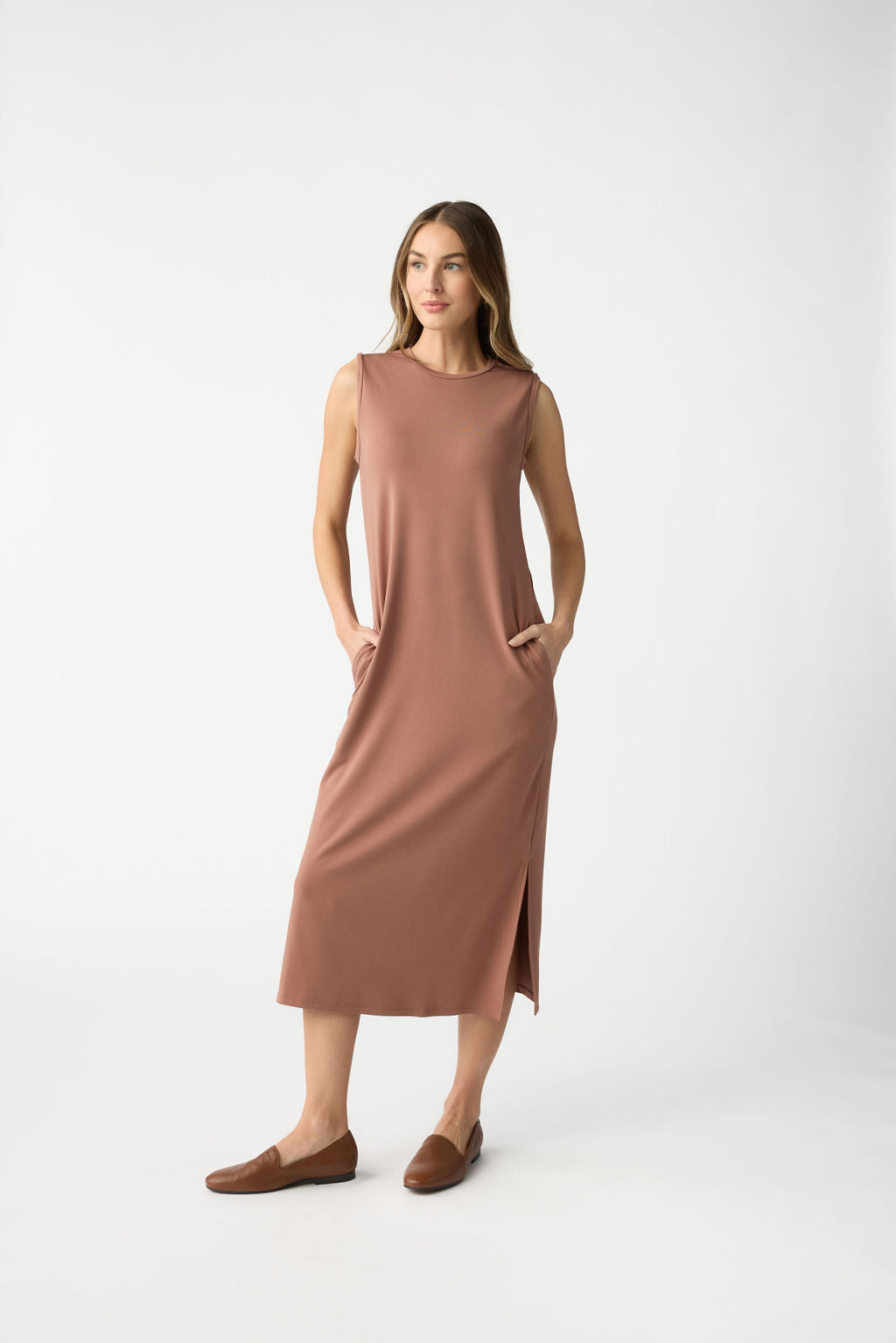 A woman with long hair wears a Cozy Earth Women's Brushed Bamboo Sleeveless Midi Dress, featuring pockets, paired with brown loafers. The background is plain white. |Color:Saddle