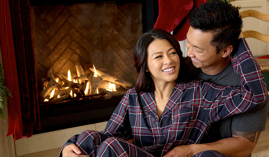 Couple in matching pajamas sitting in front of a fireplace