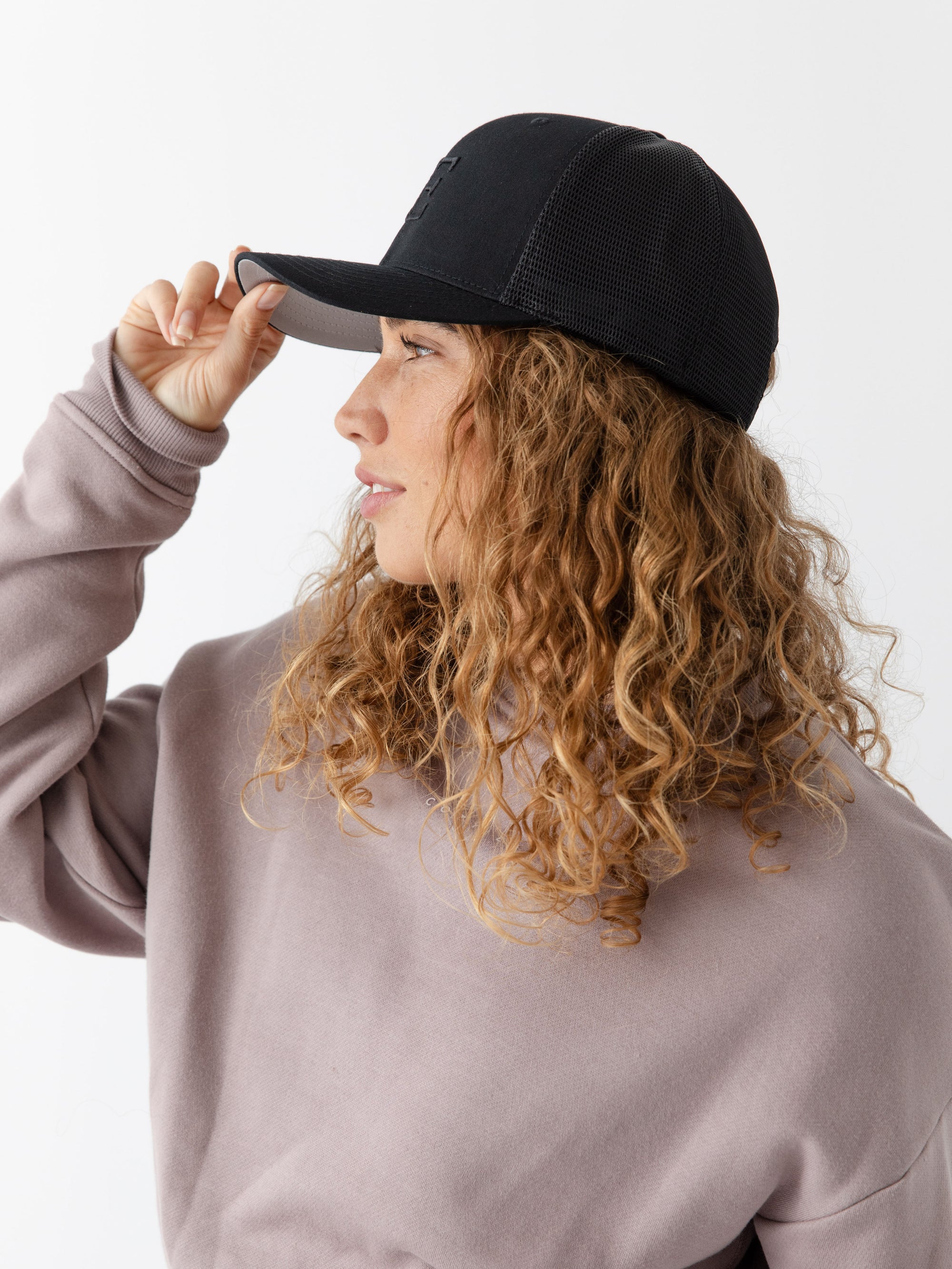 Woman wearing a black cap with a CE logo on a light gray background 