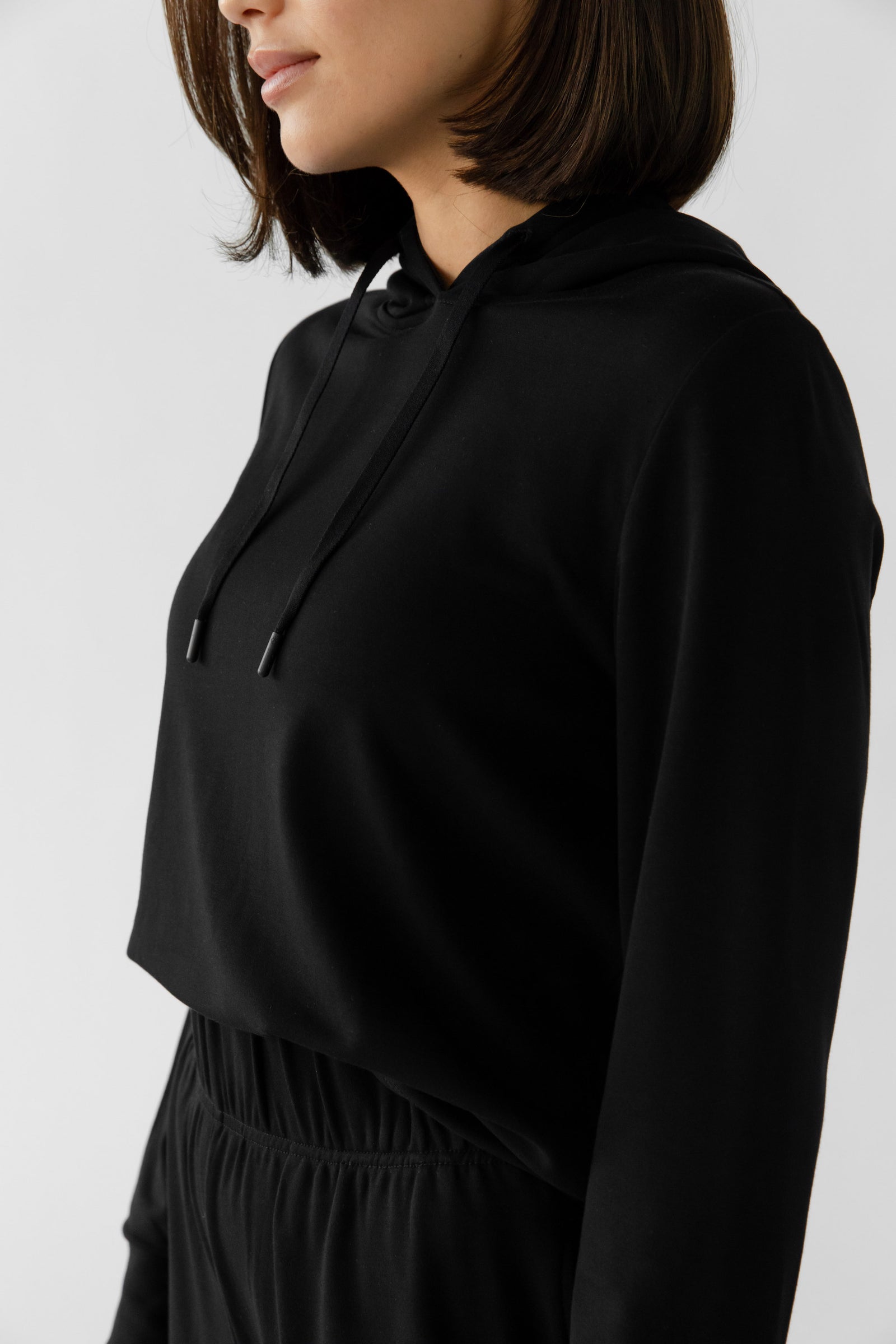 A person with shoulder-length hair is modeling the Cozy Earth Women's Ultra-Soft Bamboo Wide Leg Pull On Pant & Hoodie Set, focusing on the upper body against a plain white background. 