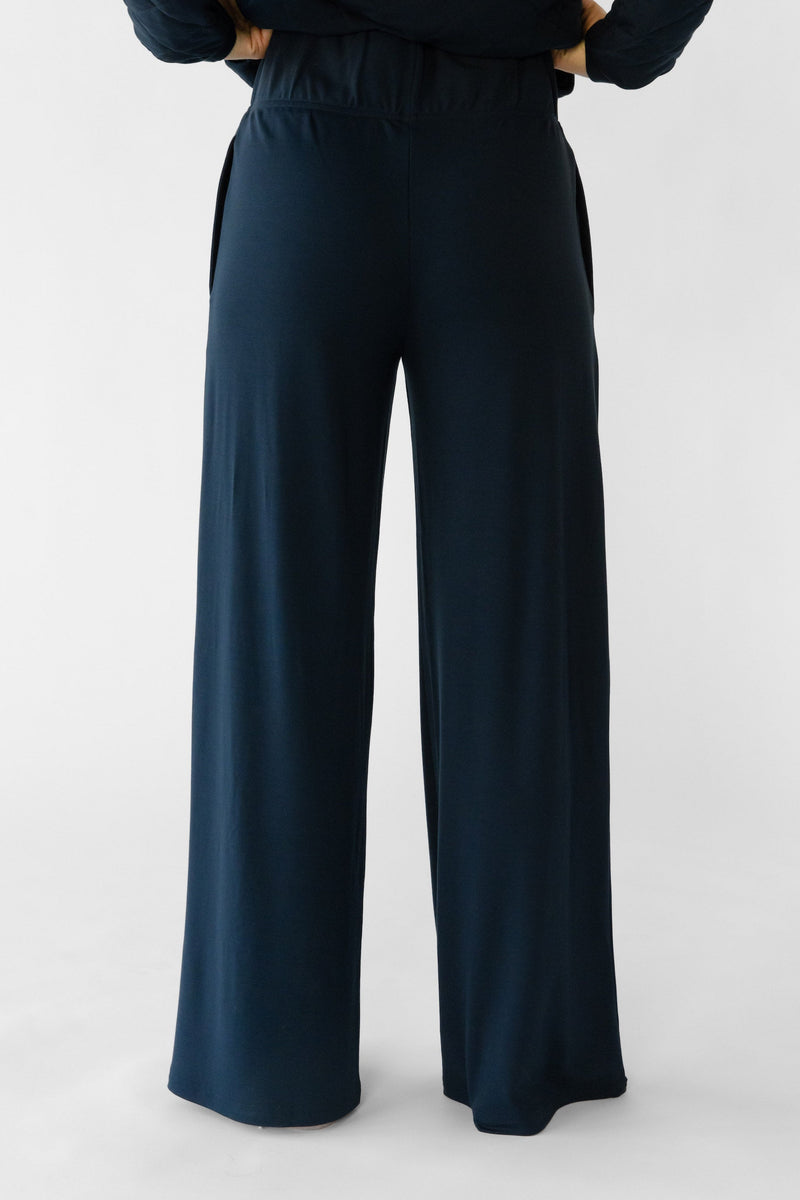 A person stands facing away from the camera in a Cozy Earth Women's Ultra-Soft Bamboo Wide Leg Pull On Pant & Pullover Set, with a plain white background.