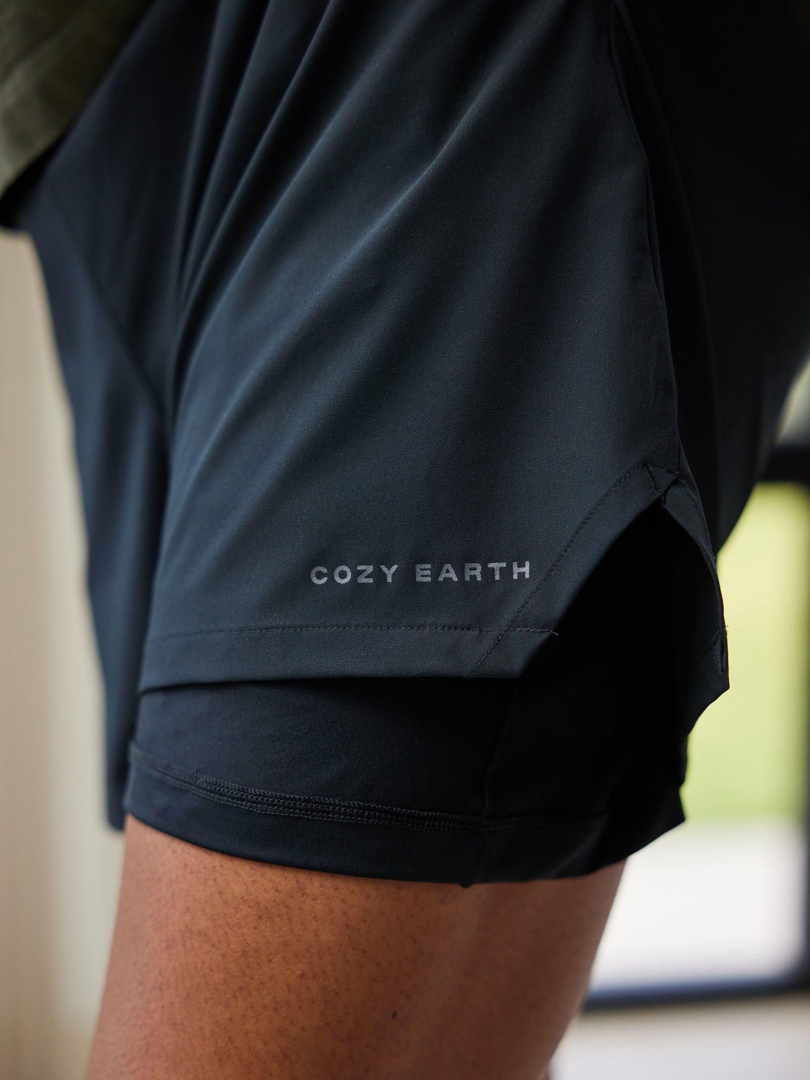 Close-up view of a person wearing the Men's Performance Sleep Short by Cozy Earth, featuring the brand's name printed on the side. The shorts appear lightweight and comfortable. 