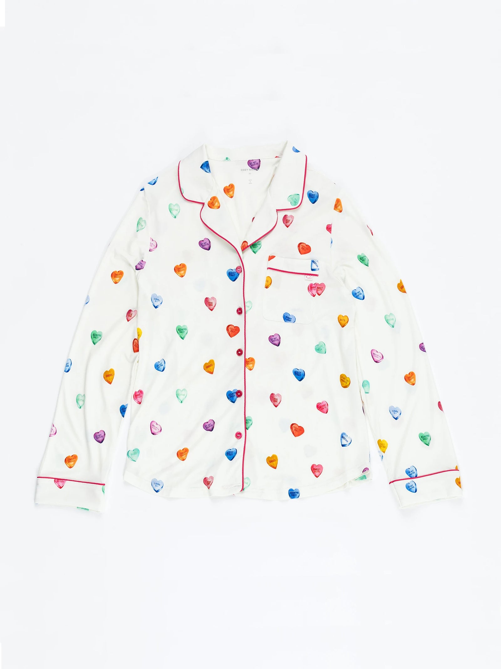 The Women's Long Sleeve Bamboo Pajama Top in Stretch-Knit by Cozy Earth features a white base with colorful hearts in blue, green, red, and orange. It includes red piping on the collar, button placket, and cuffs plus a chest pocket. 