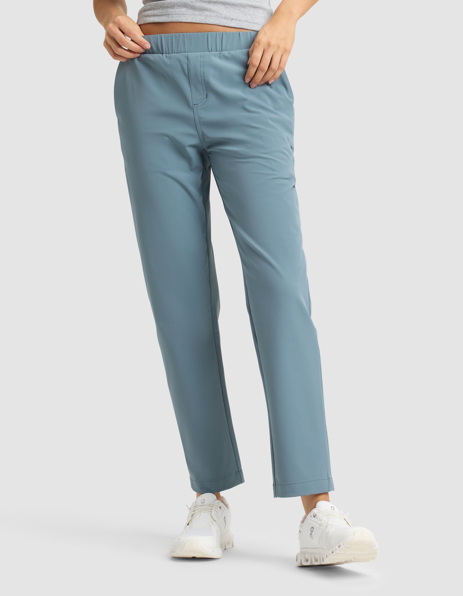 A person wears Cozy Earth's Women's Always Cropped Pant in light blue, paired with a gray top and white sneakers, standing against a plain light background. Only the lower body is shown. 