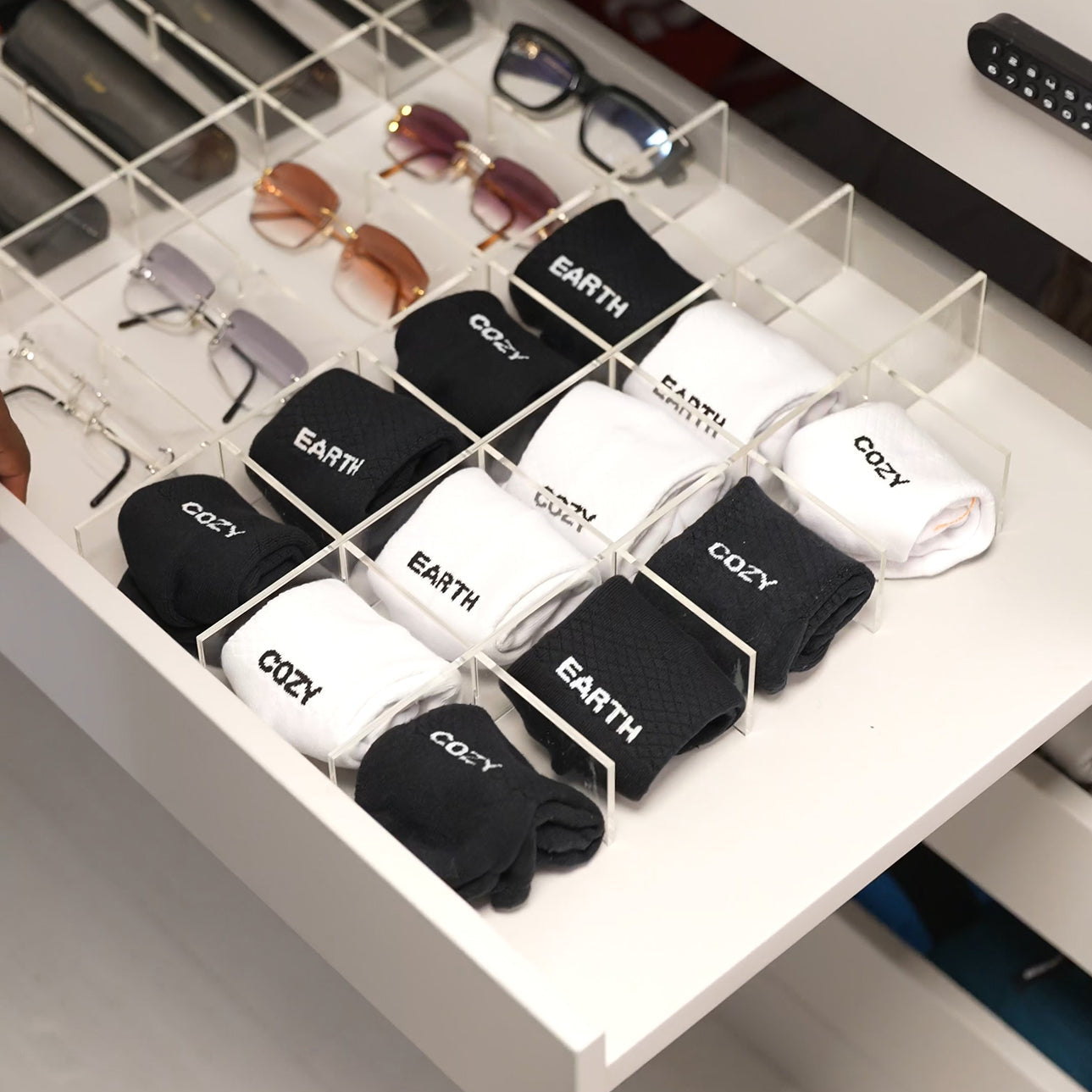 Black and white socks with 'COZY' and 'EARTH' text in a clear organizer.