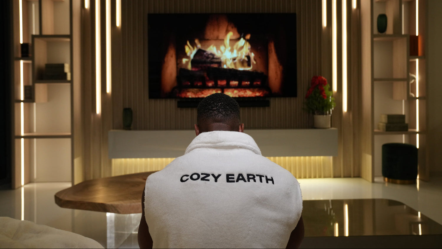 Ashton Hall sitting in front of a fireplace with a cozy earth robe