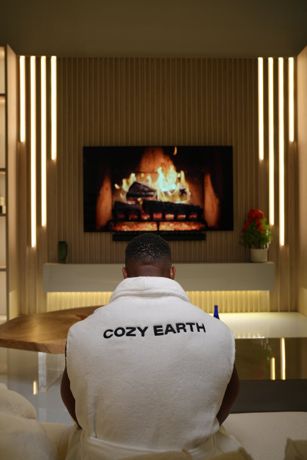 Ashton Hall sitting in front of a fireplace with a cozy earth robe