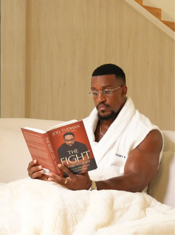 Ashton Hall reading a book in bed