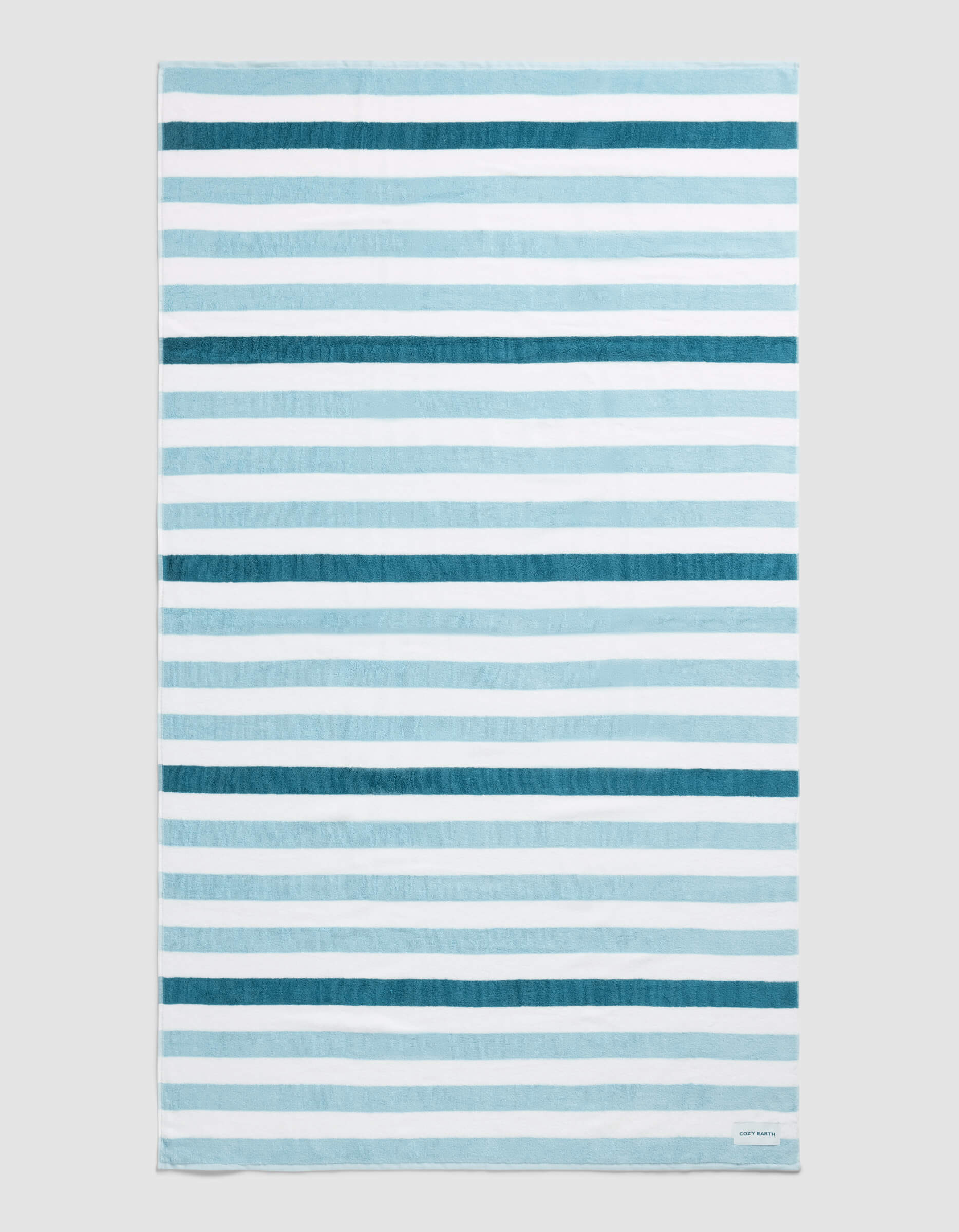 The Cozy Earth Classic Stripe Resort Towel in Lake Stripe features horizontal blue and white stripes of varying thickness and intensity, displayed flat on a neutral background.