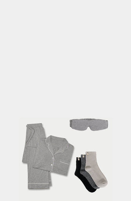 Set of gray pajama pants, shirt, socks, and eye mask on a white background