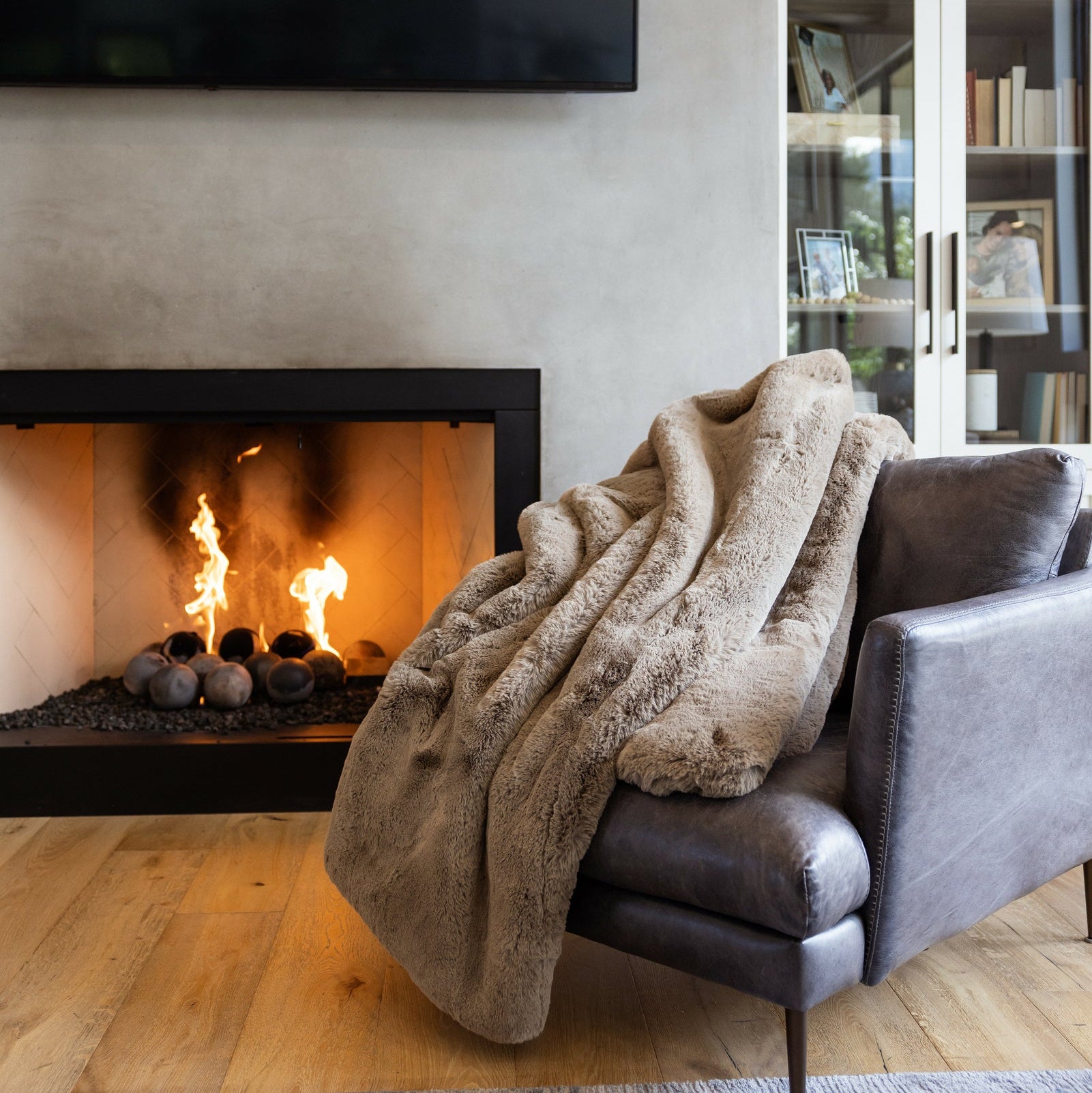 Cozy living room with a blanket draped over a chair next to a fireplace