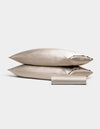 Two Bamboo Bedding Basic Bundle pillowcases by Cozy Earth, in light beige, are stacked with a matching folded sleep mask in front, all set against a plain light gray background.|Color:Driftwood