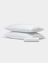Two white rectangular pillows from the Cozy Earth Bamboo Bedding Basic Bundle are stacked, with a matching small cylindrical bolster in front, all set against a plain light gray background.|Color:White