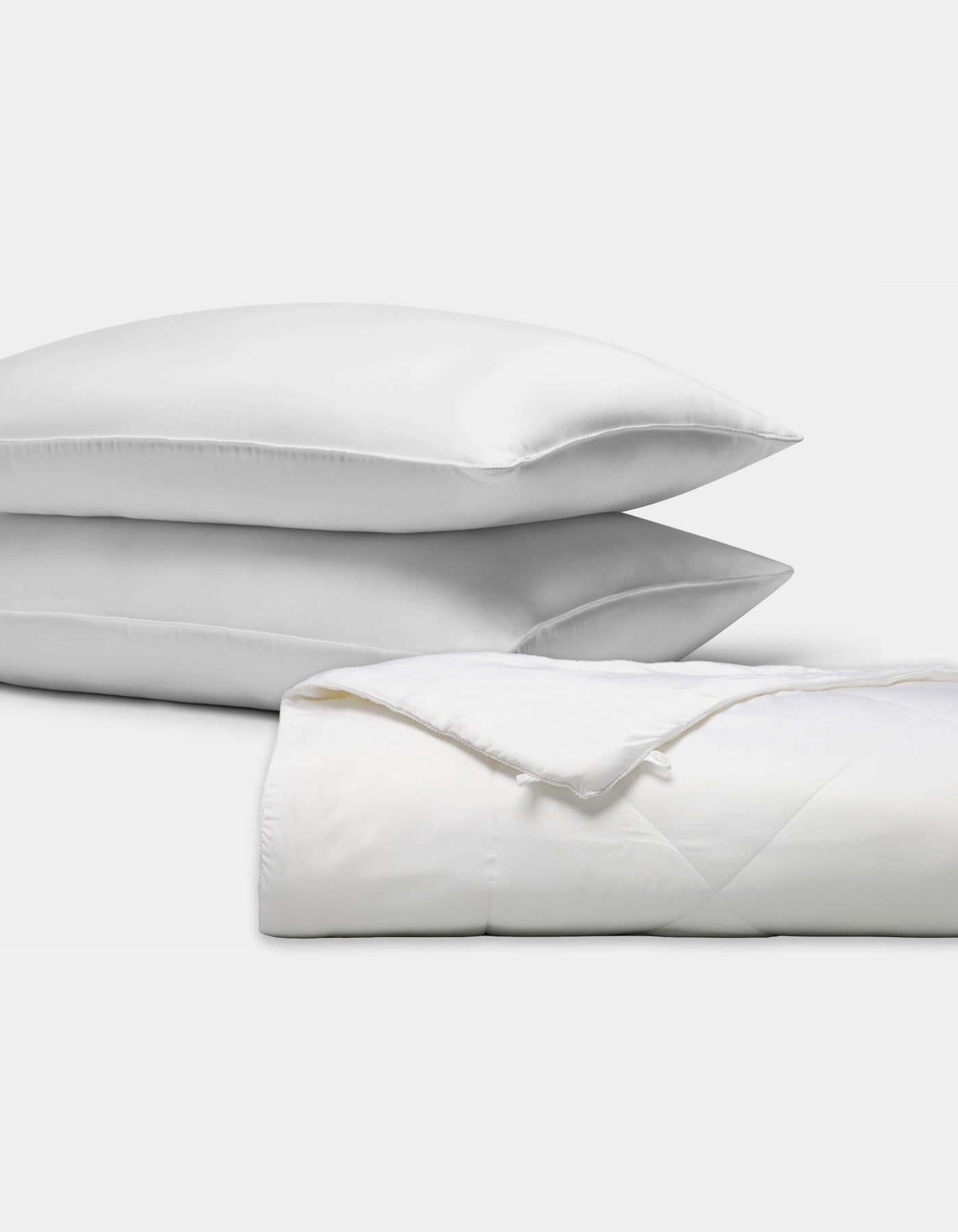 The Cozy Earth Bamboo Insert Bundle features two plush white pillows stacked beside a neatly folded white comforter, all displayed on a plain white background.|Filling:Standard