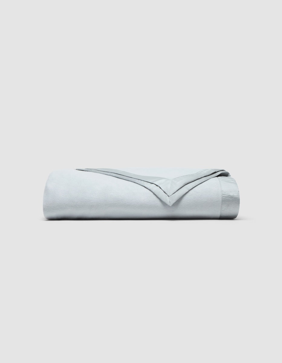 A folded light blue Cozy Earth Bamboo Blanket with a satin border.