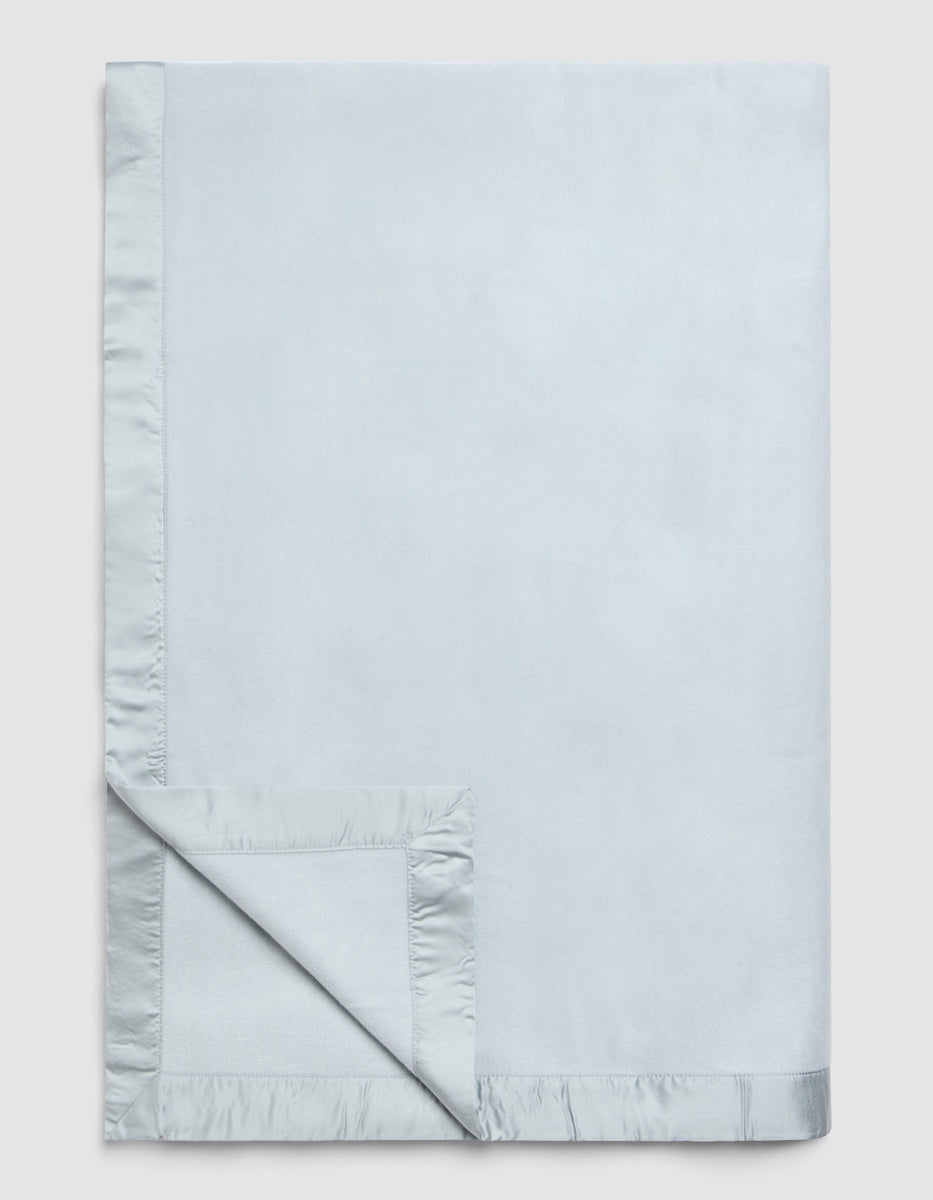 Light blue Bamboo Blanket with a wide, ruffled hem, shown folded at one corner.