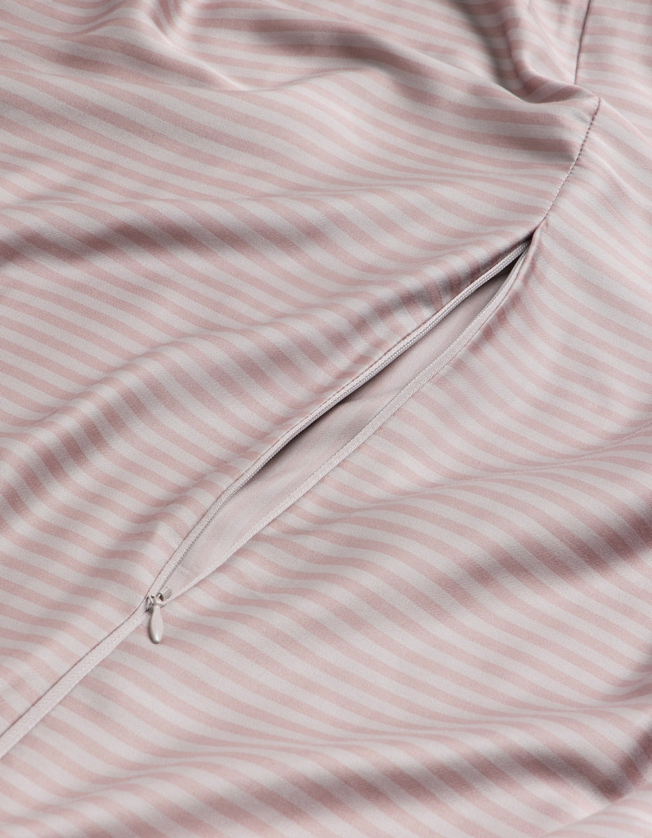 A close-up of the lavender striped Bamboo Duvet Cover by Cozy Earth highlights a partially open, concealed zipper pocket with a small pull tab.