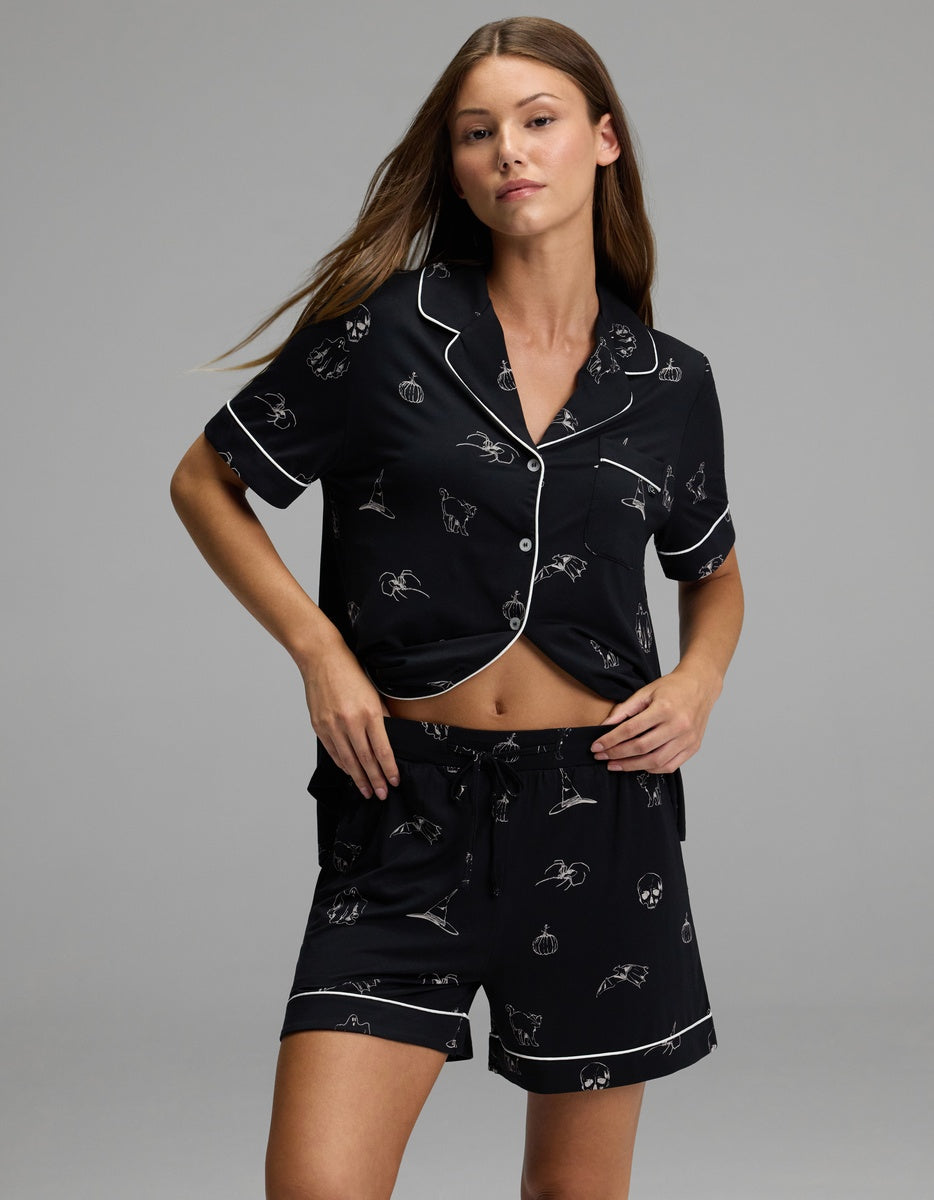 A woman wearing the Cozy Earth Women’s Bamboo Stretch-Knit Short Sleeve Pajama Set stands against a plain gray background.