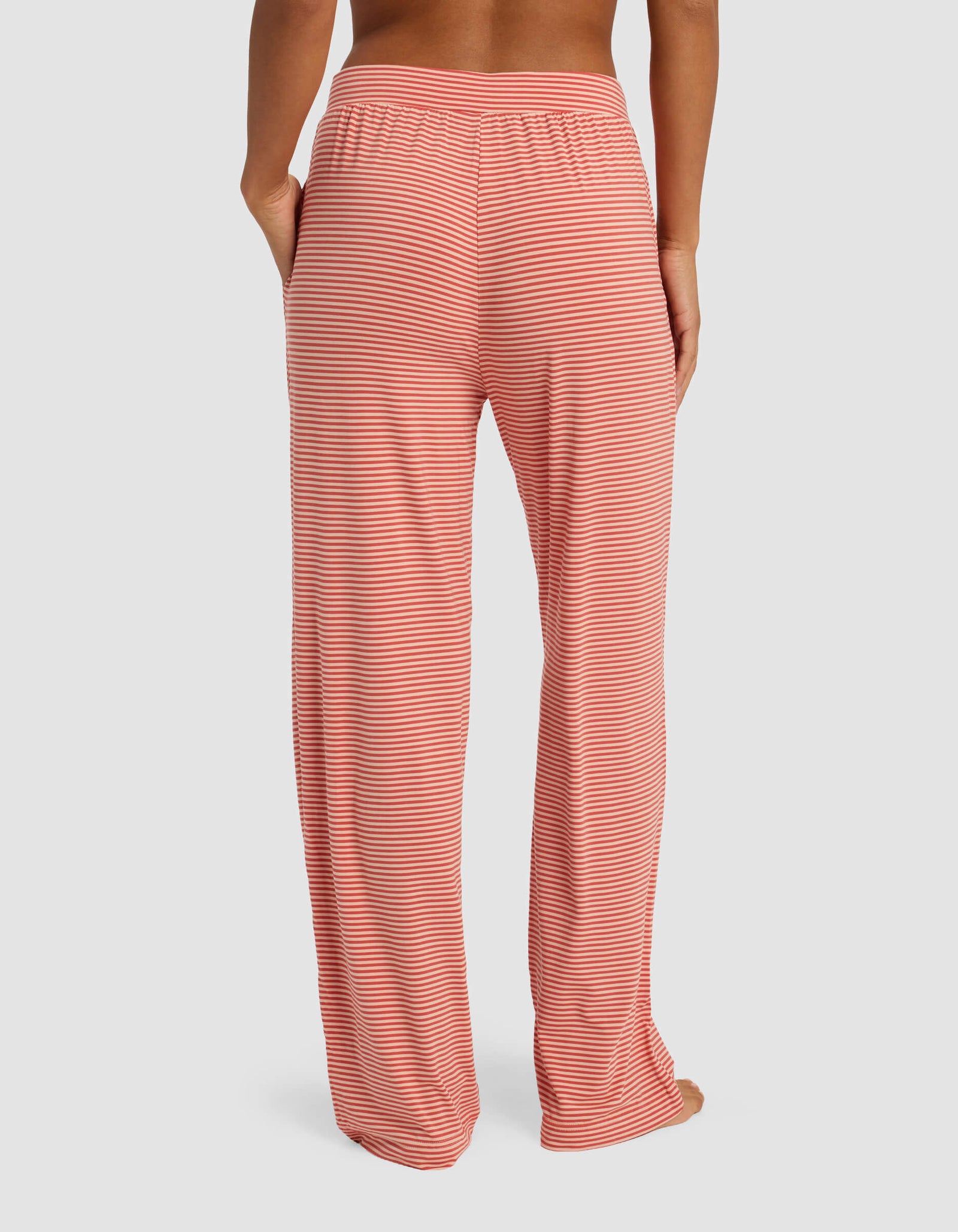 A person is shown from the waist down, standing barefoot against a plain background, wearing Cozy Earth Women's Bamboo Stretch-Knit Pant with a loose fit and hands in pockets.