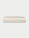 A neatly folded Bamboo Jersey Fitted Sheet by Cozy Earth in plain cream is displayed against a white background.|Color:Birch