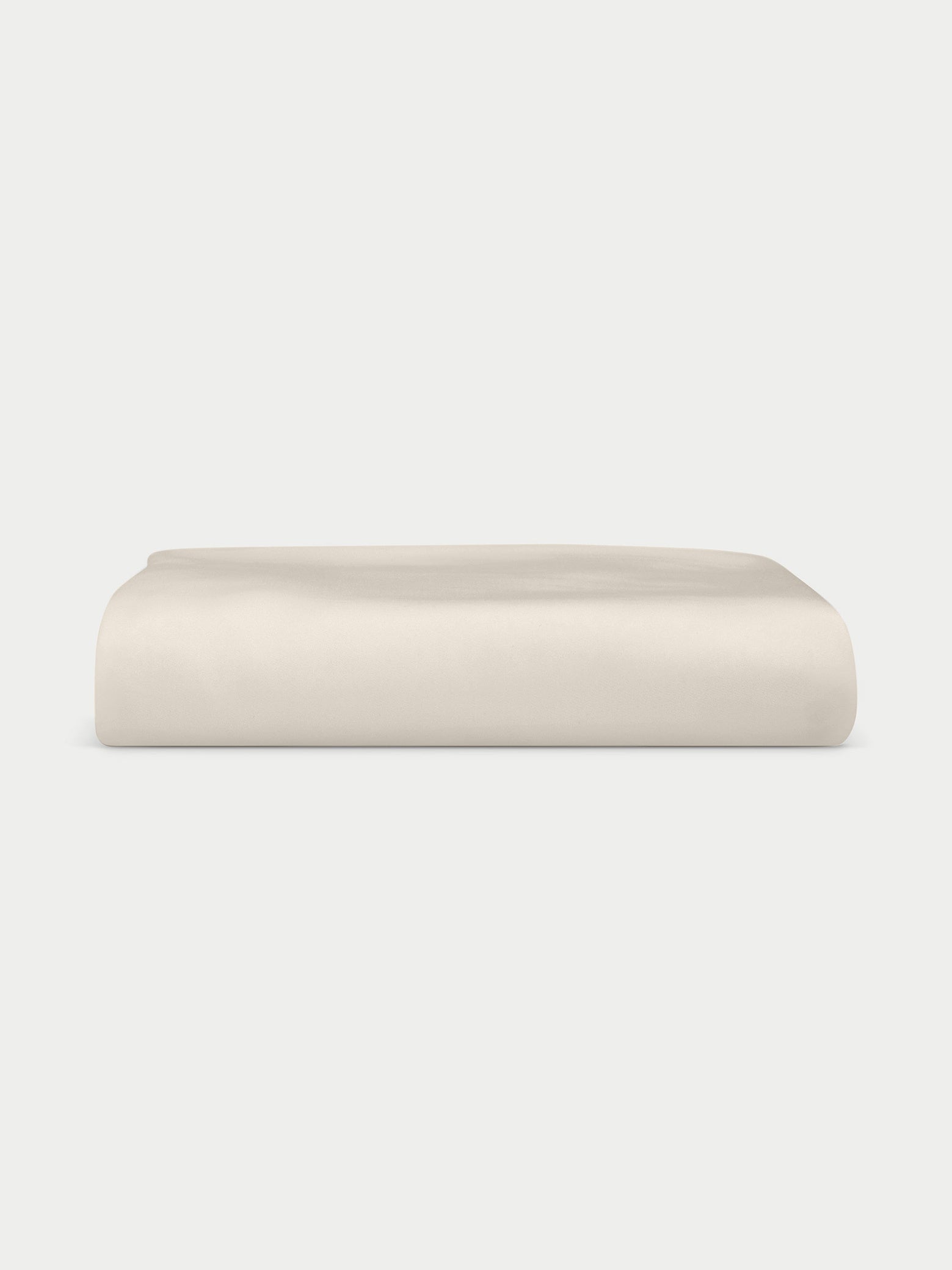 A neatly folded Bamboo Jersey Fitted Sheet by Cozy Earth in plain cream is displayed against a white background.|Color:Birch