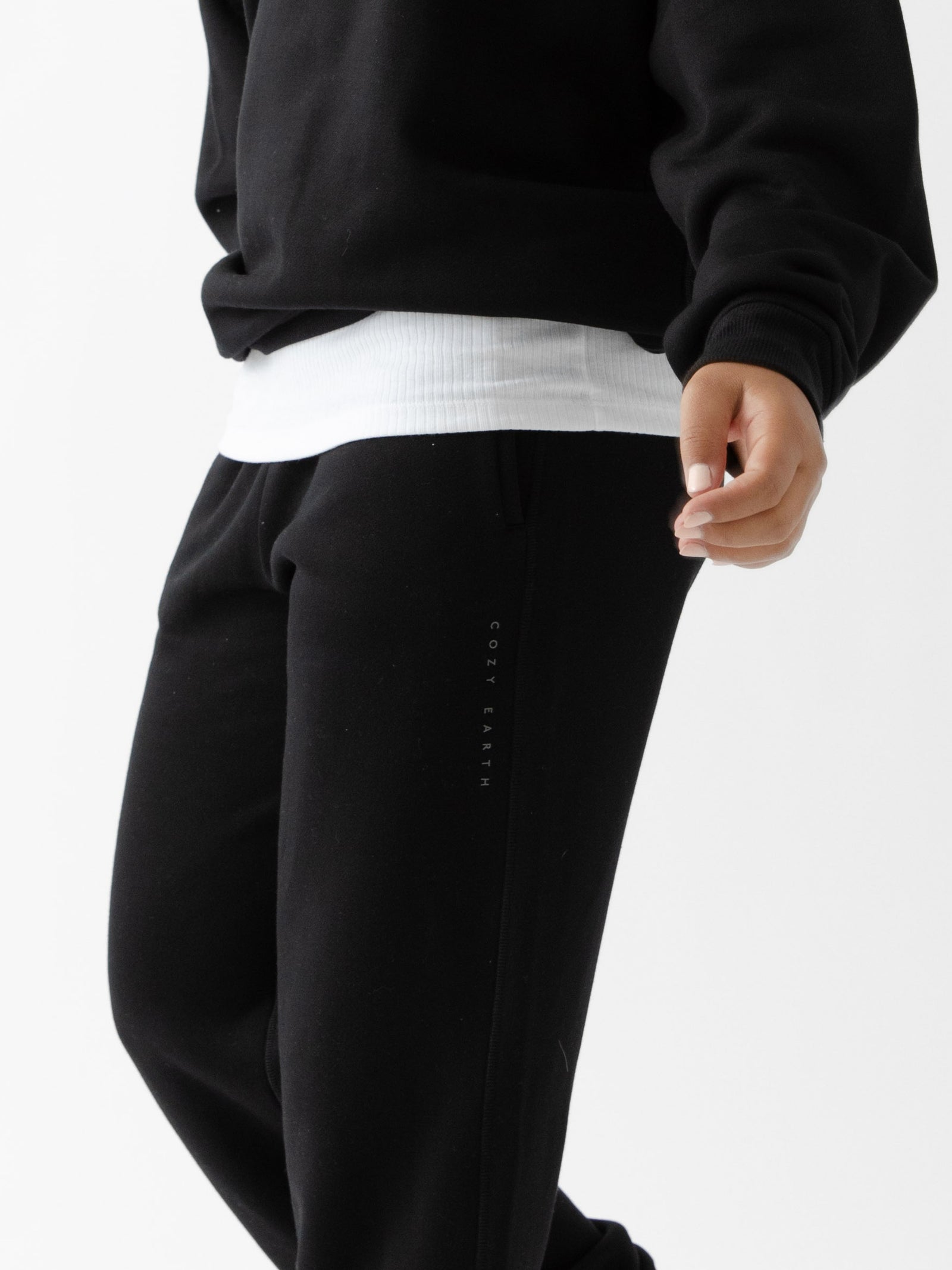Black CityScape Joggers. The Joggers are being worn by a female model. The photo is taken from the waist down. The back ground is white. 