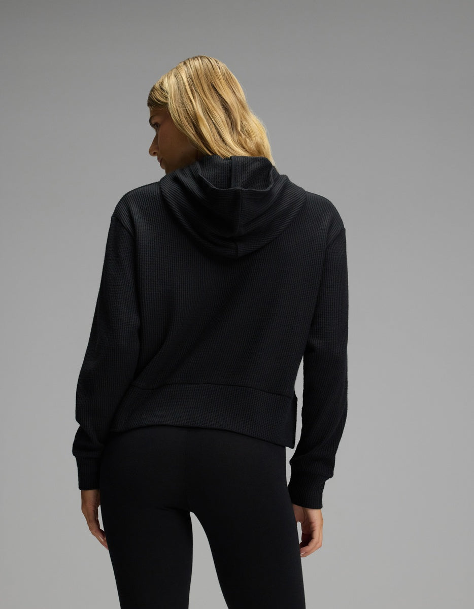 Back view of a person wearing a black long-sleeve Women’s Blake Waffle Hoodie.